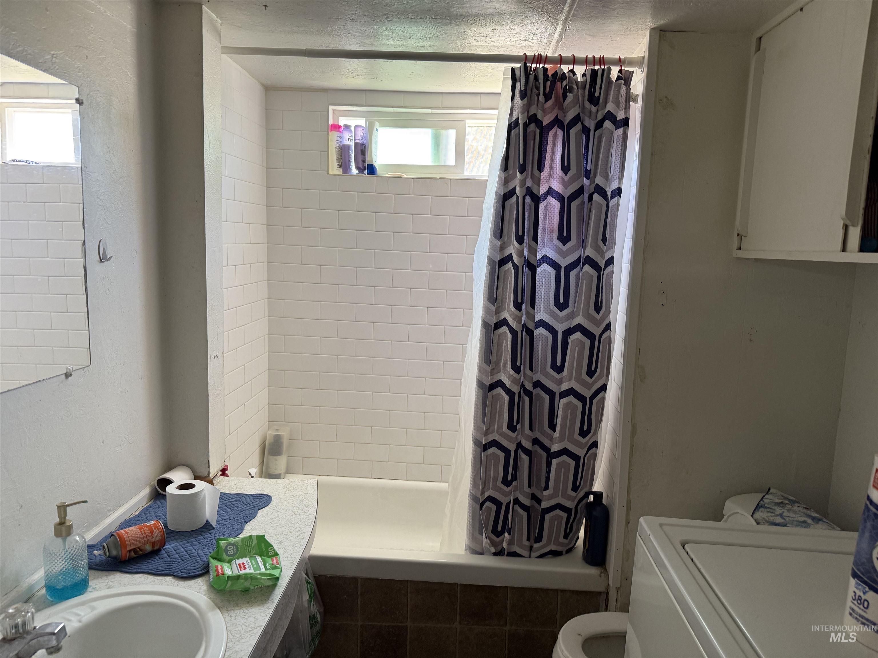 Bathroom with tiled shower / bath, vanity, and washer / dryer