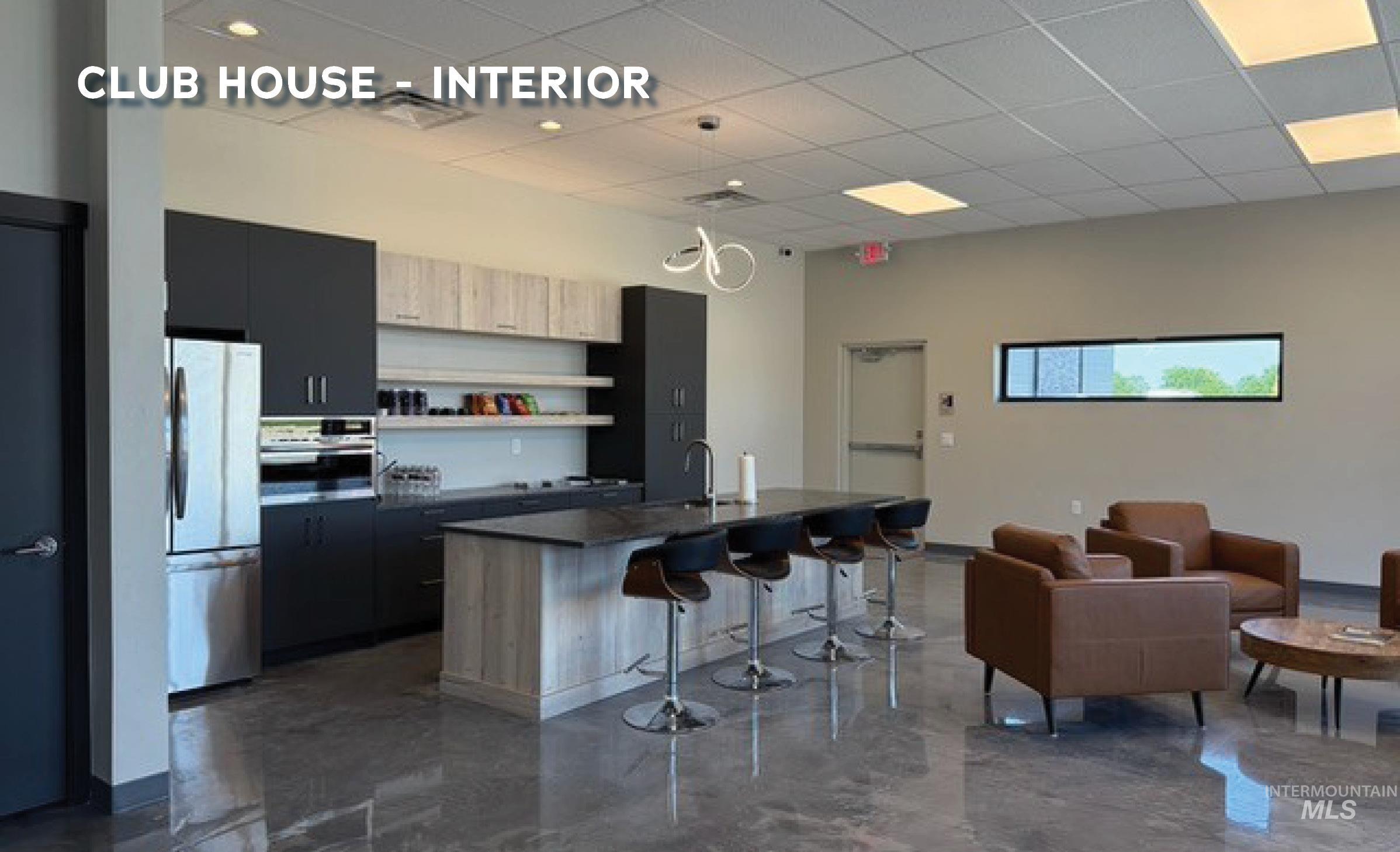 Kitchen with a breakfast bar, freestanding refrigerator, dark countertops, dark cabinetry, and a center island with sink