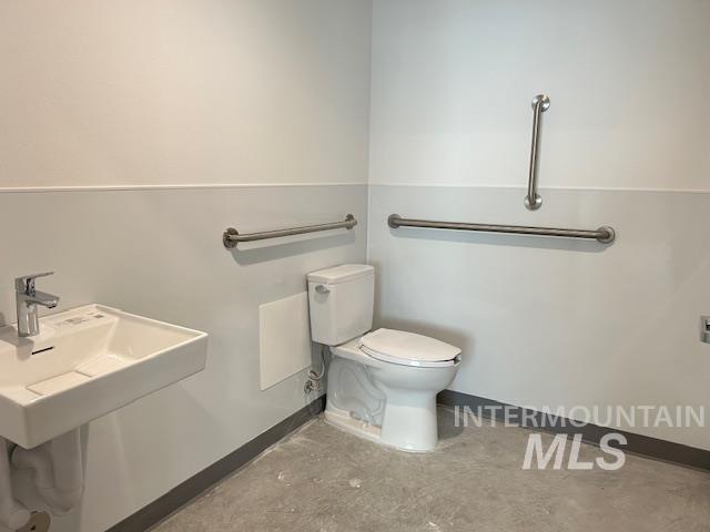 Half bath with baseboards and unfinished concrete flooring