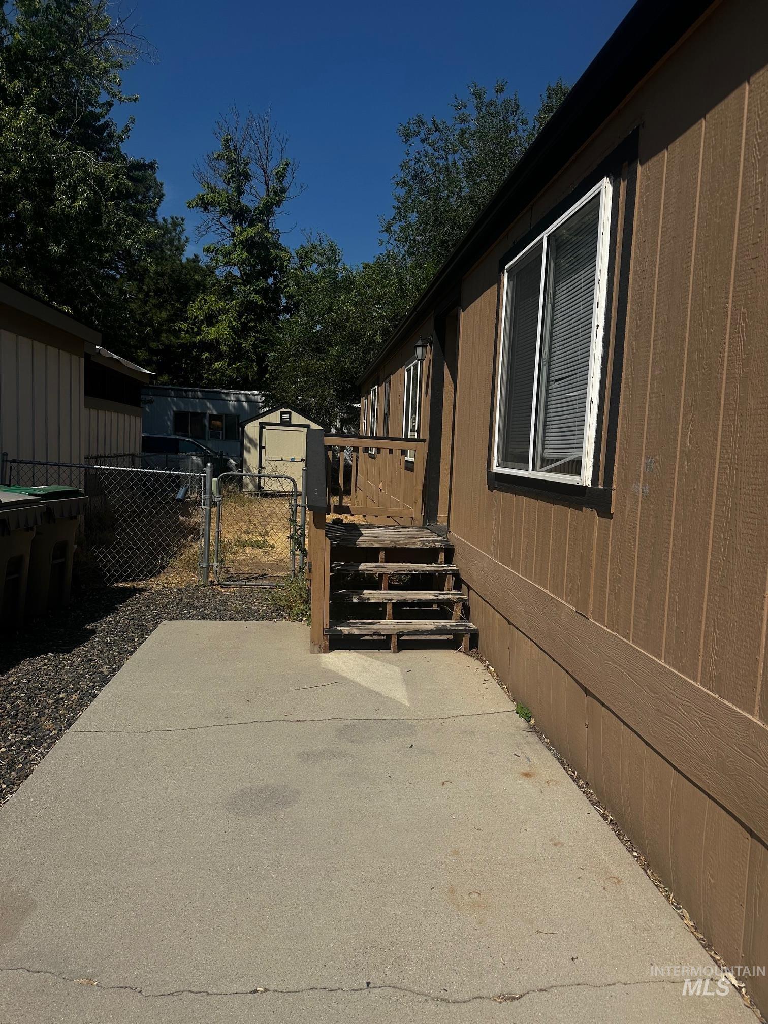 View of side of property featuring a gate, a patio area, and an outbuilding