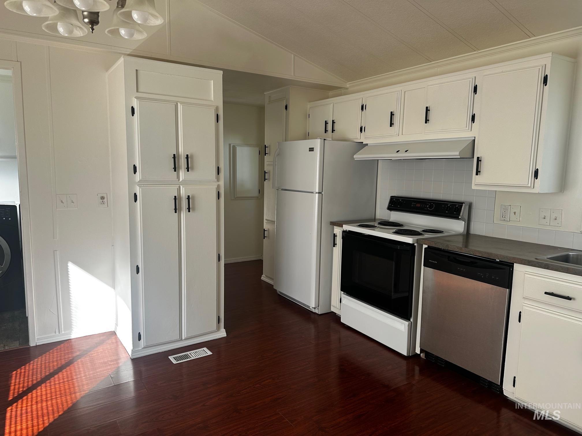 Kitchen with white cabinets, range with electric cooktop, dark countertops, stainless steel dishwasher, and vaulted ceiling