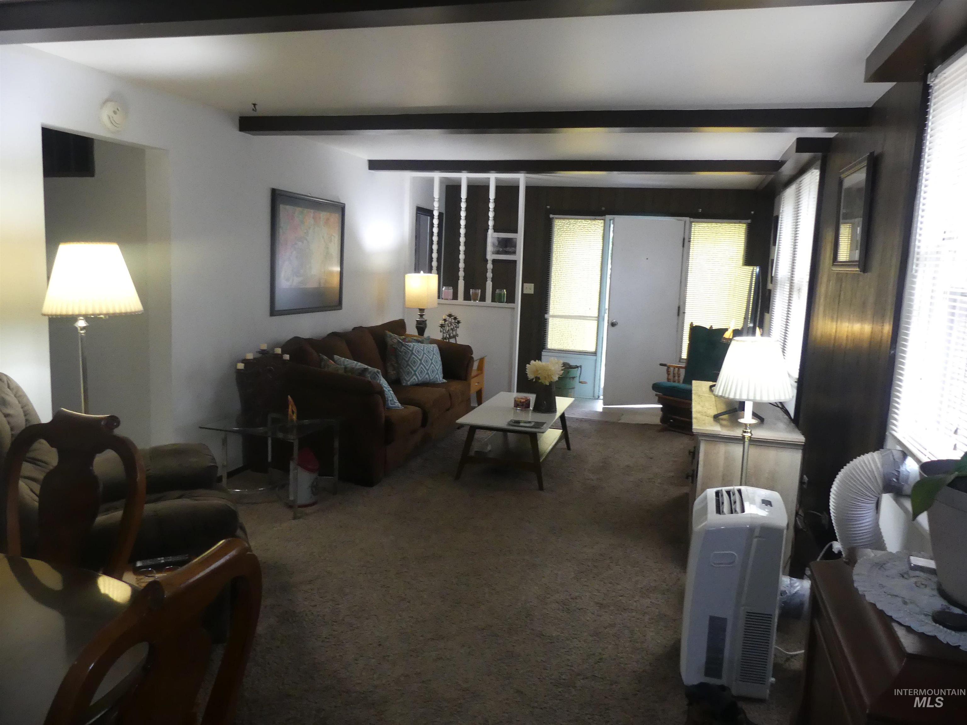 Carpeted living room featuring healthy amount of natural light and beam ceiling
