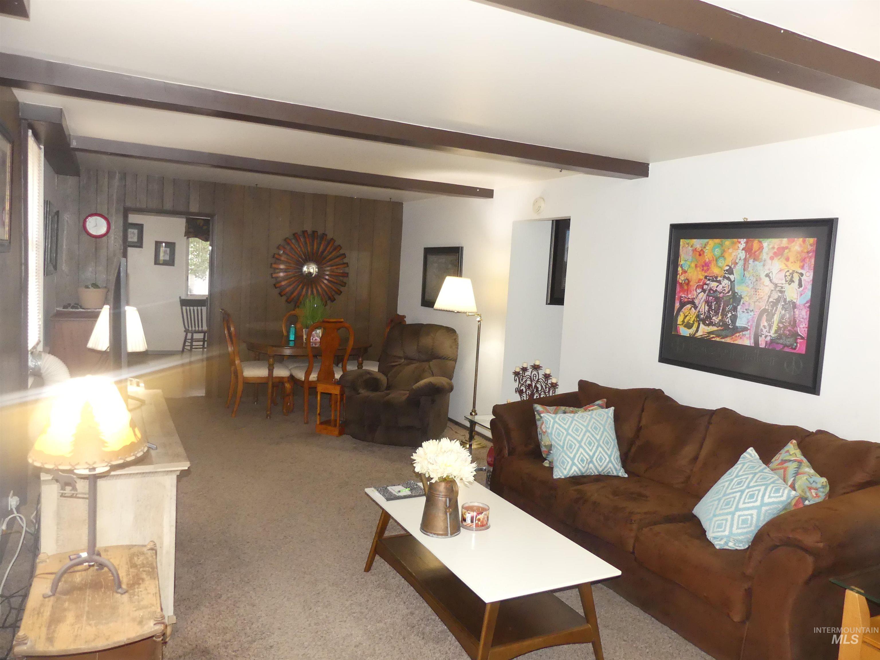 Carpeted living room featuring beamed ceiling