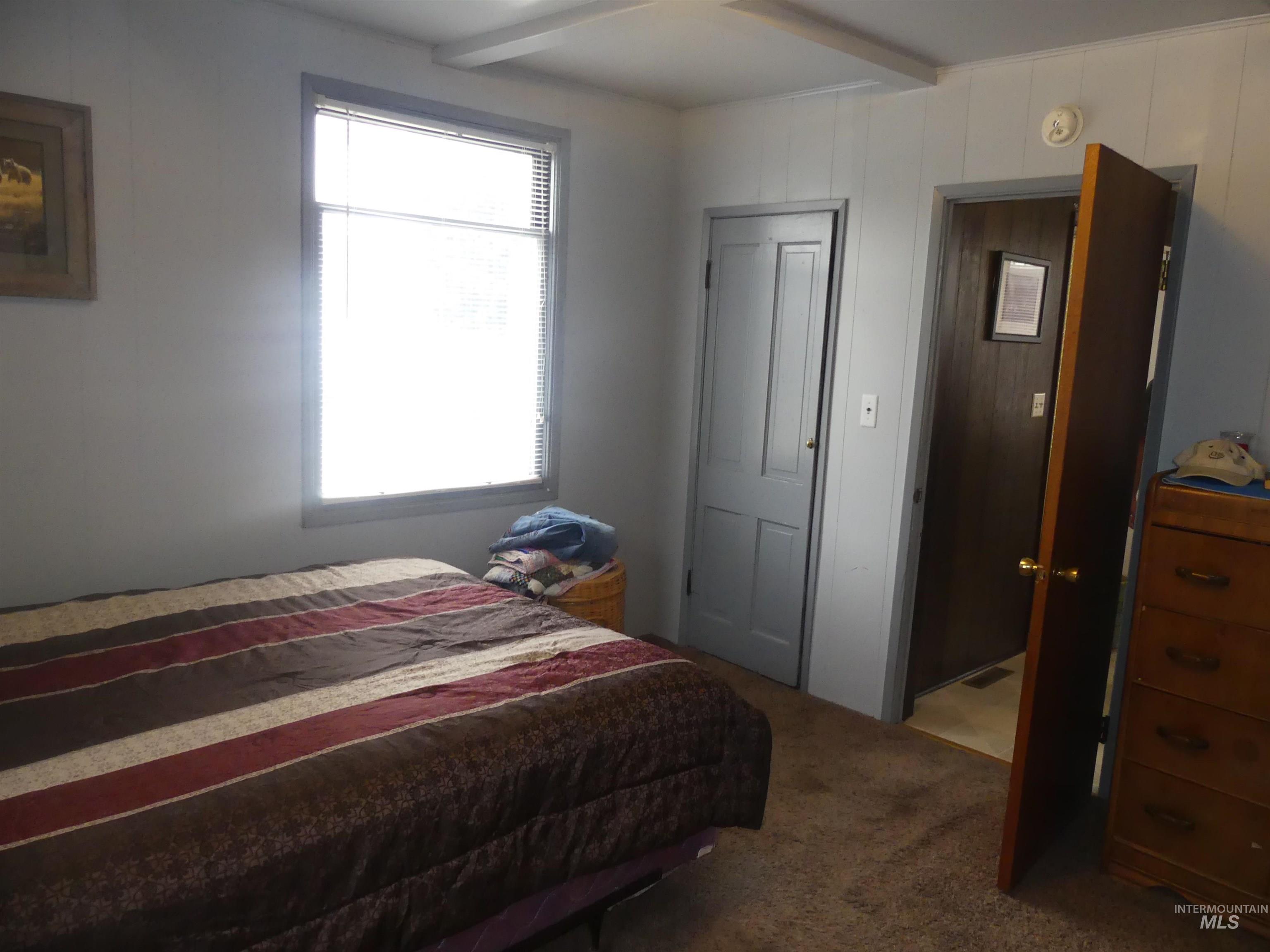 Bedroom featuring carpet floors, beamed ceiling, and wood walls