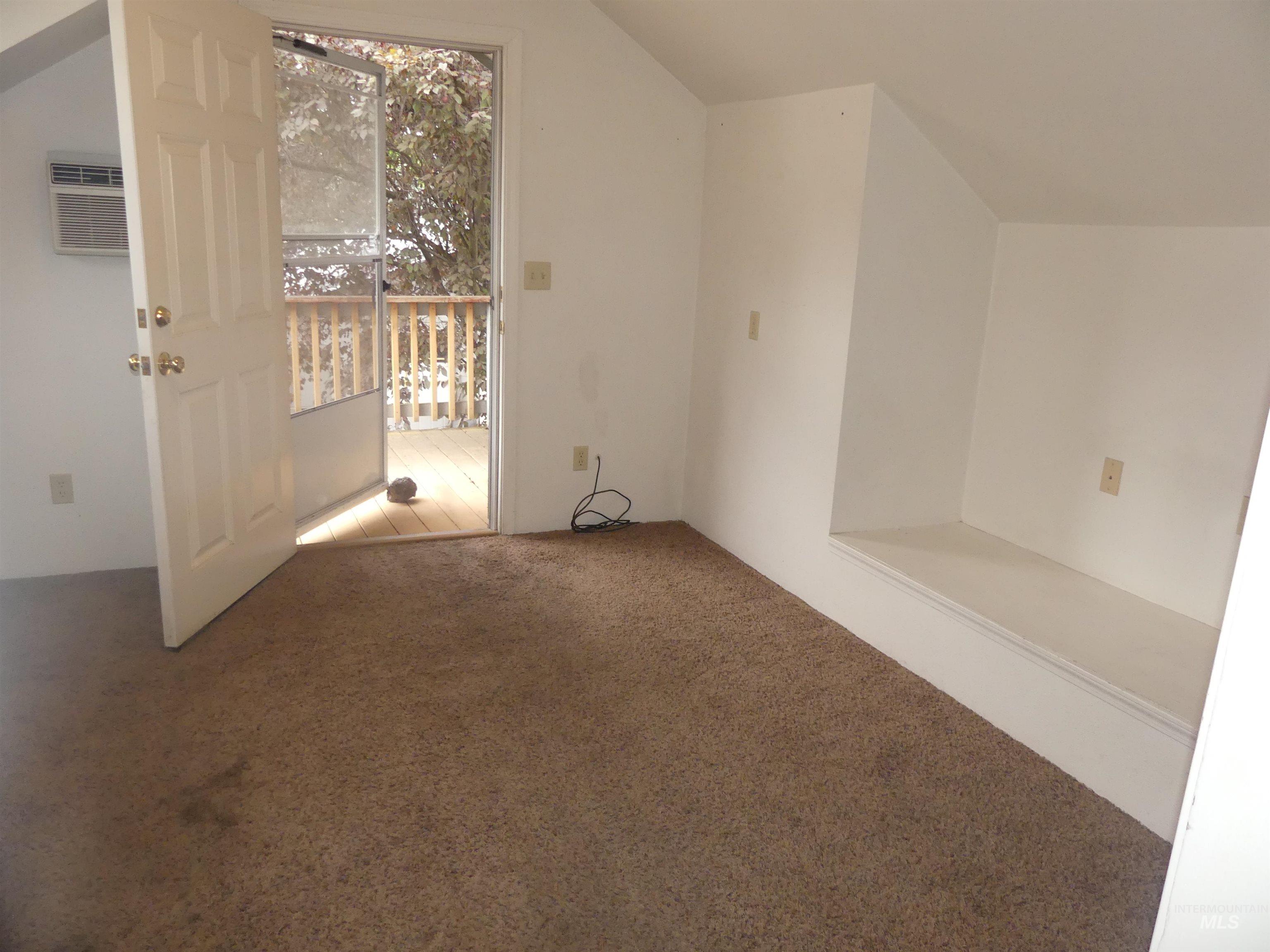 Additional living space with carpet floors, lofted ceiling, and a wall mounted air conditioner