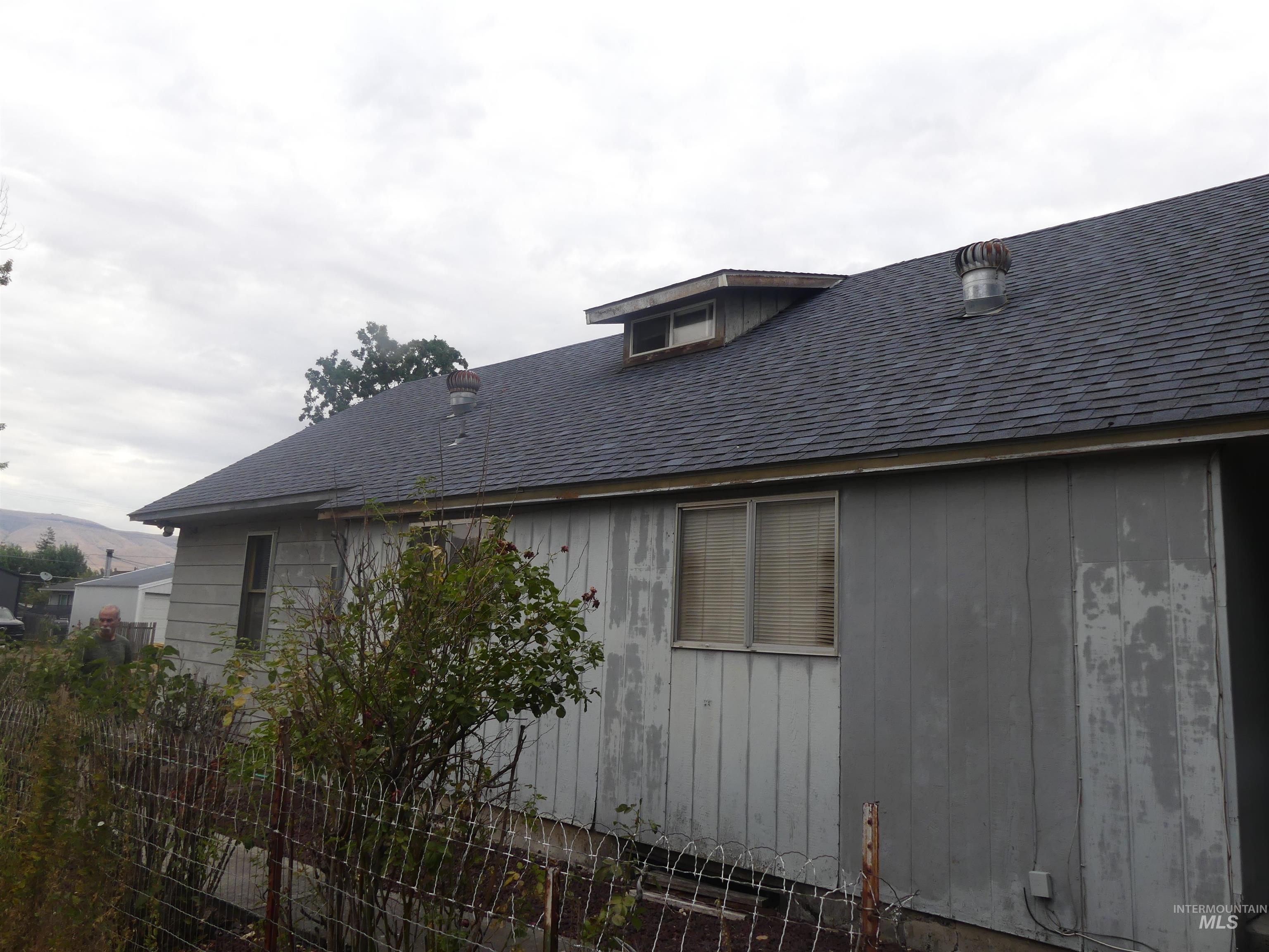 View of side of home with roof with shingles