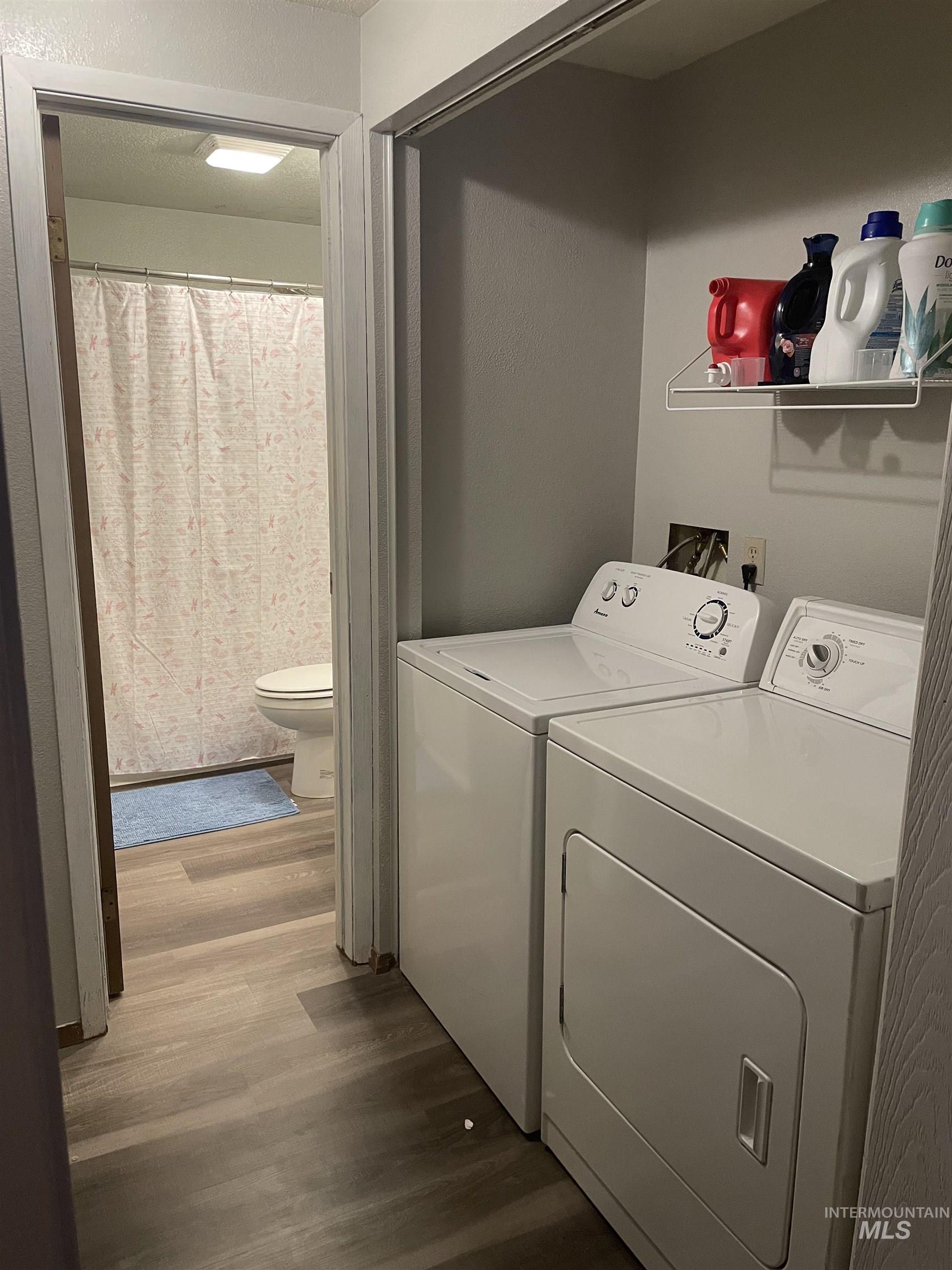 Laundry room with washing machine and dryer and wood finished floors