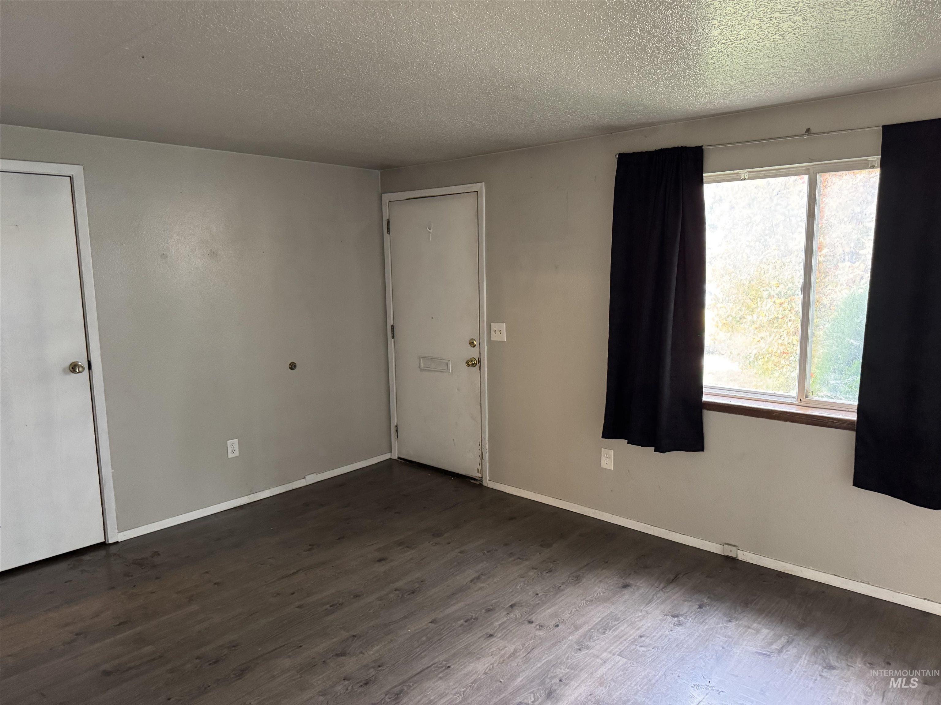 Spare room with dark wood-style floors and a textured ceiling