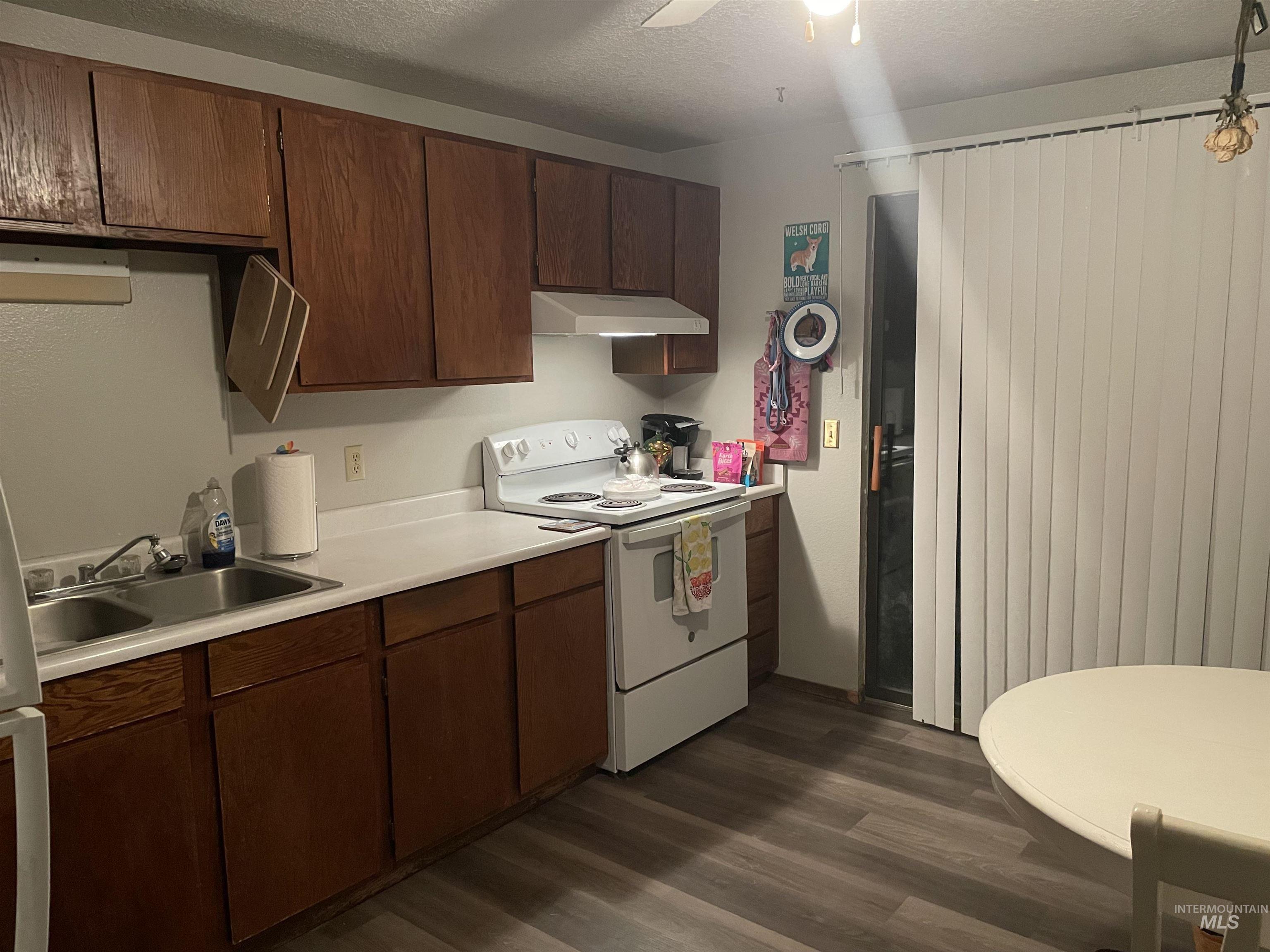 Kitchen featuring white electric range oven, light countertops, dark wood-type flooring, ventilation hood, and a textured ceiling