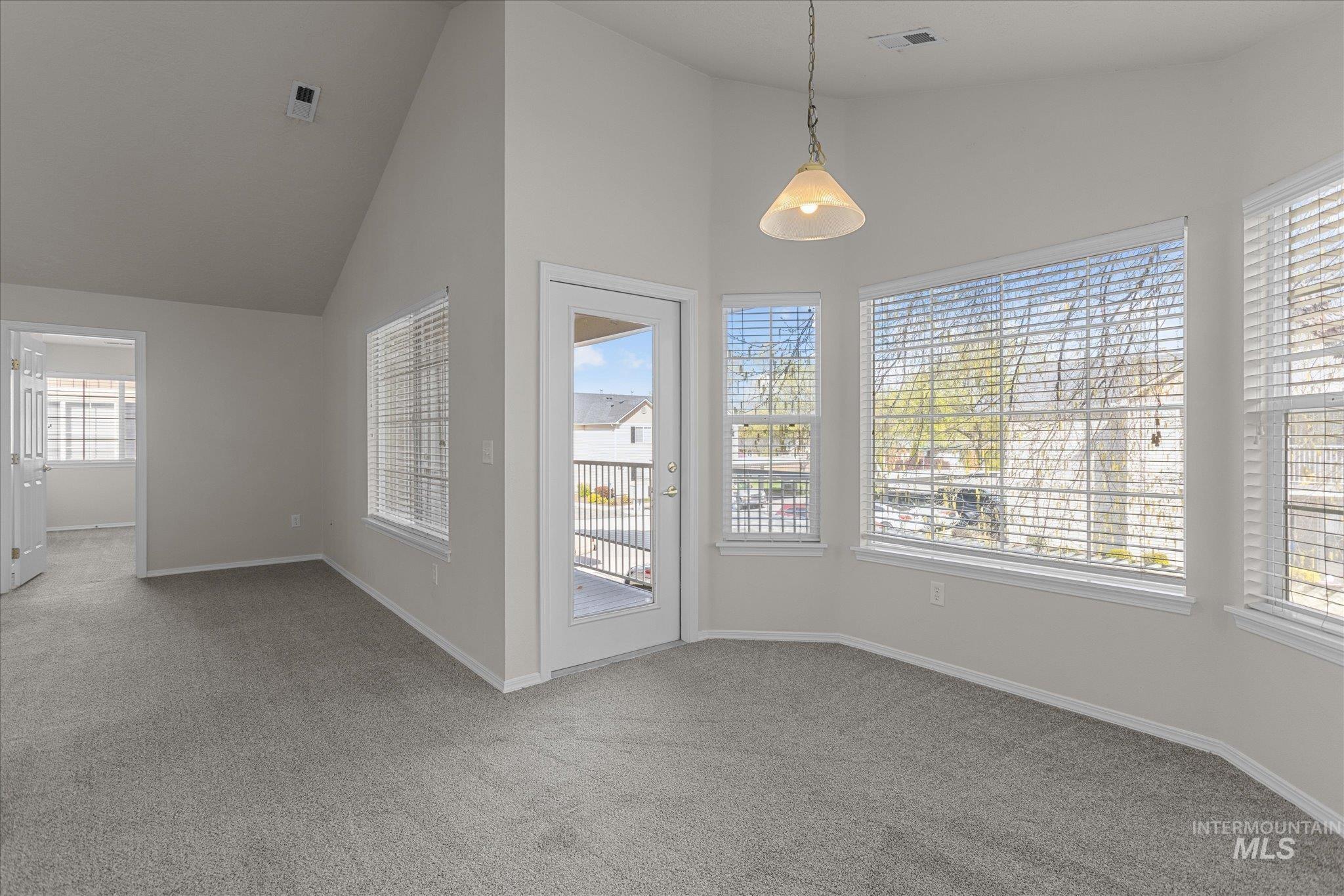 Unfurnished dining area with high vaulted ceiling, carpet, and healthy amount of natural light