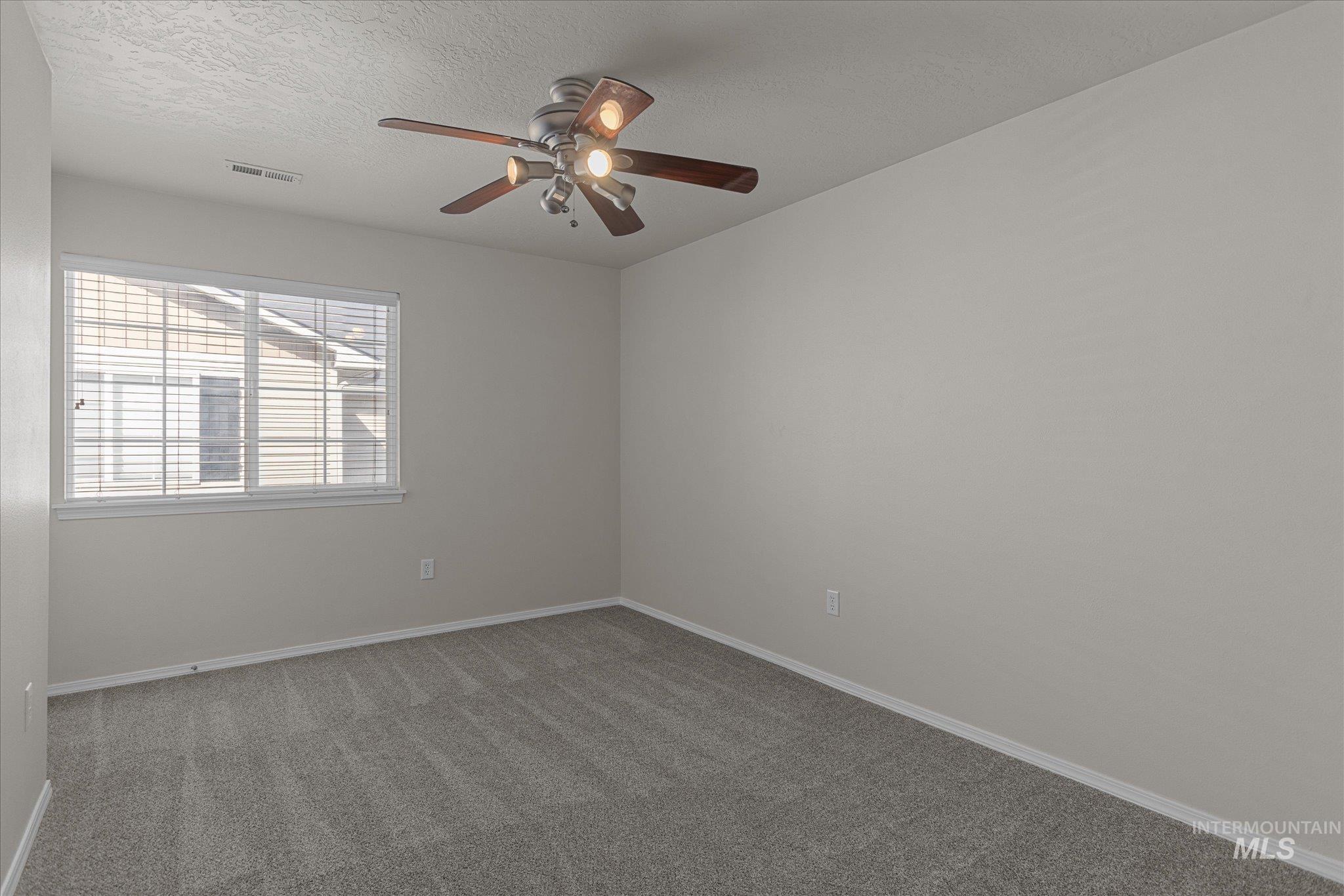 Unfurnished room with carpet flooring, a textured ceiling, and ceiling fan