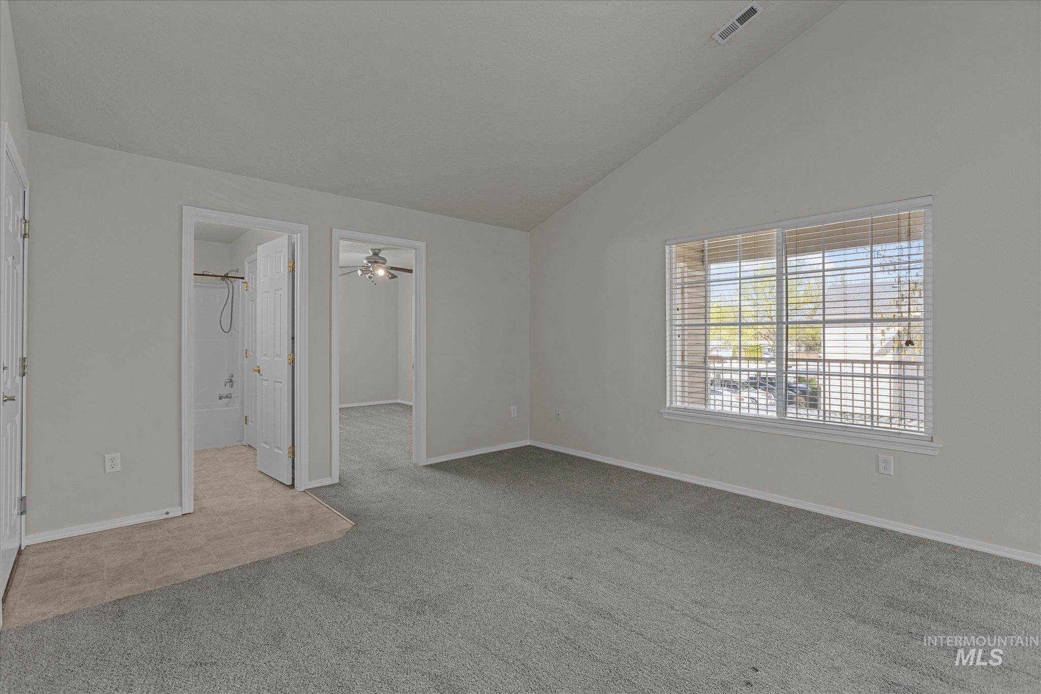 Unfurnished bedroom with carpet, a spacious closet, and high vaulted ceiling