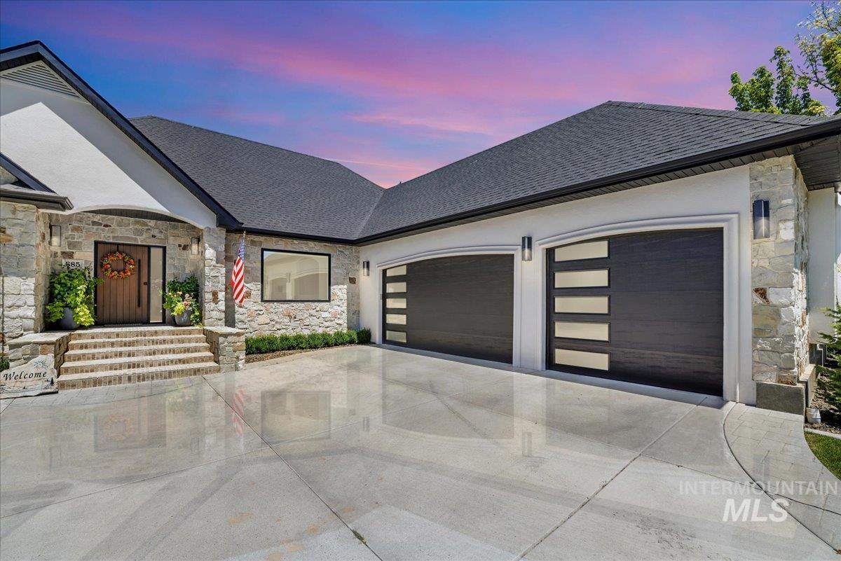 View of front of house featuring stone siding, a garage, and driveway