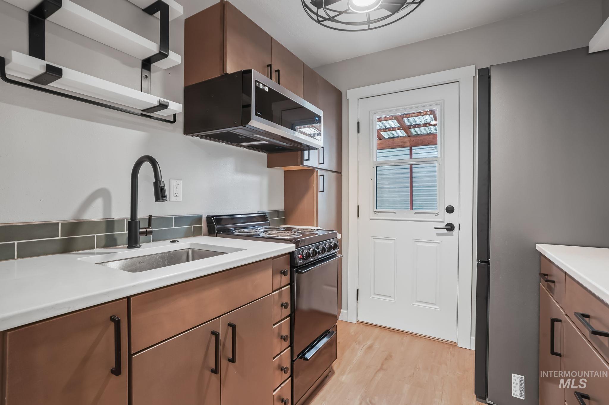 Kitchen featuring black/SS appliances (no dishwasher), quartz counters