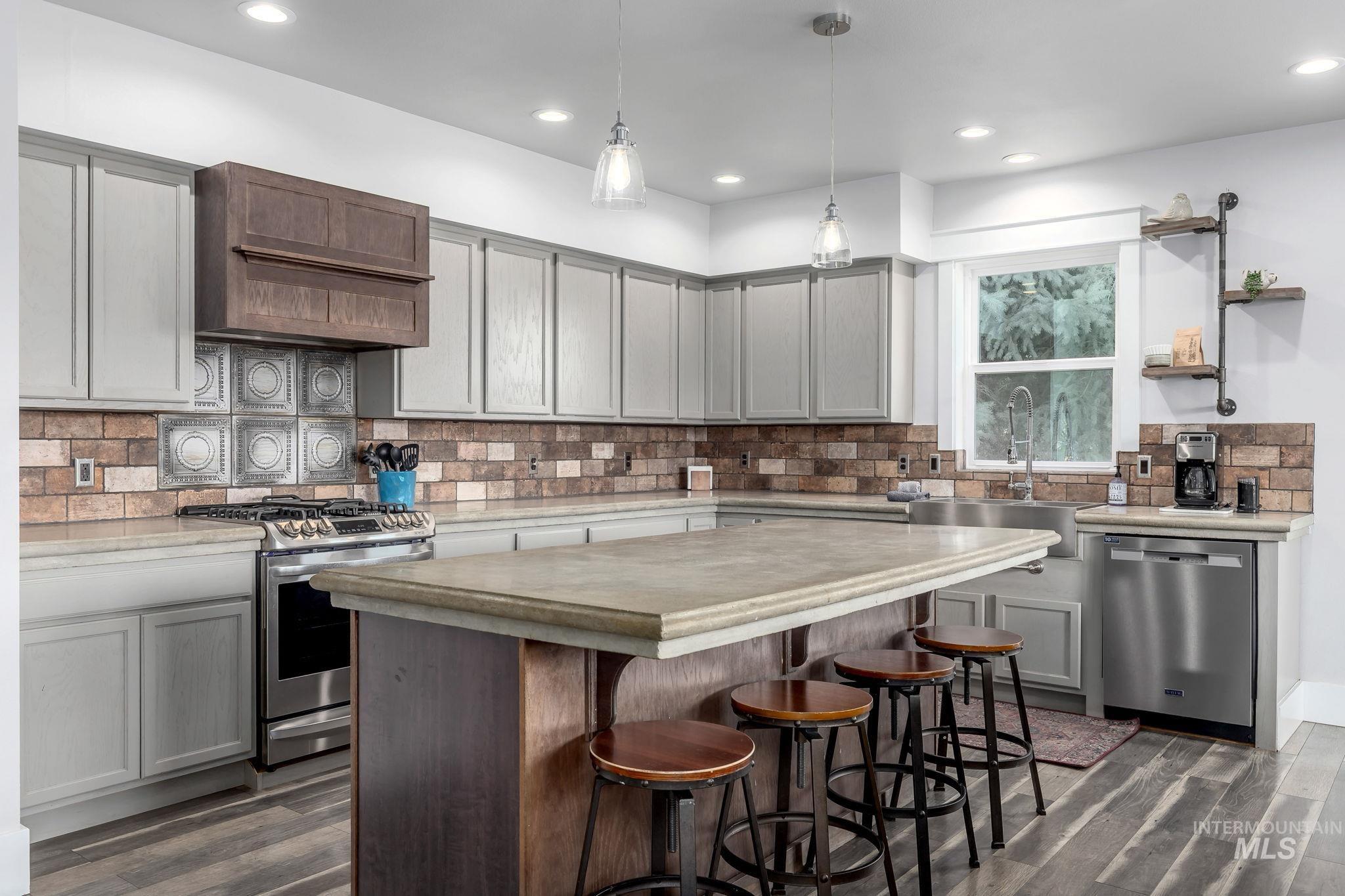 Kitchen with appliances with stainless steel finishes, dark wood-type flooring, decorative backsplash, recessed lighting, and light countertops
