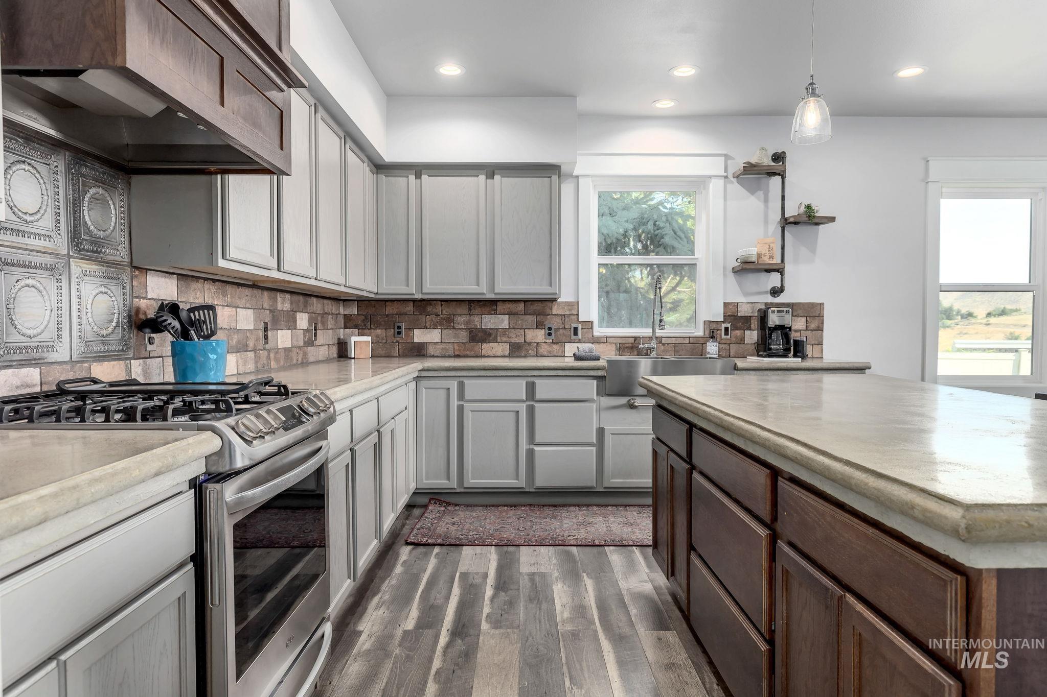Kitchen featuring stainless steel range with gas cooktop, dark wood-style floors, light countertops, recessed lighting, and custom exhaust hood