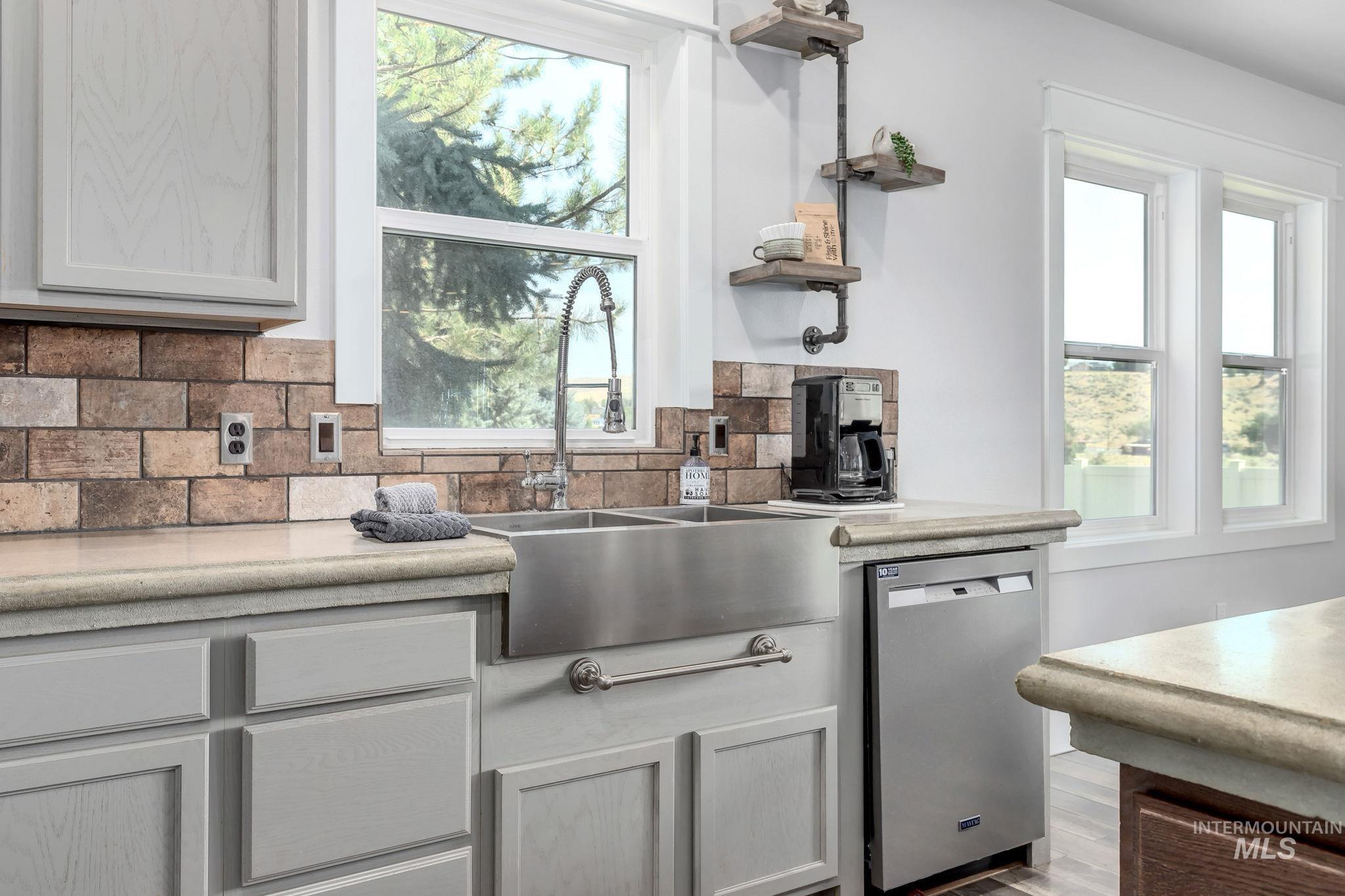 Kitchen with open shelves, dishwasher, backsplash, and light countertops