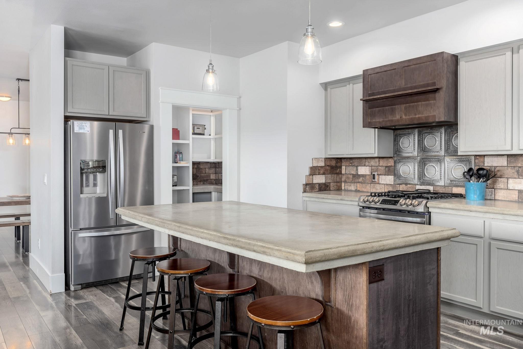 Kitchen featuring appliances with stainless steel finishes, dark wood-style floors, decorative backsplash, a kitchen island, and premium range hood