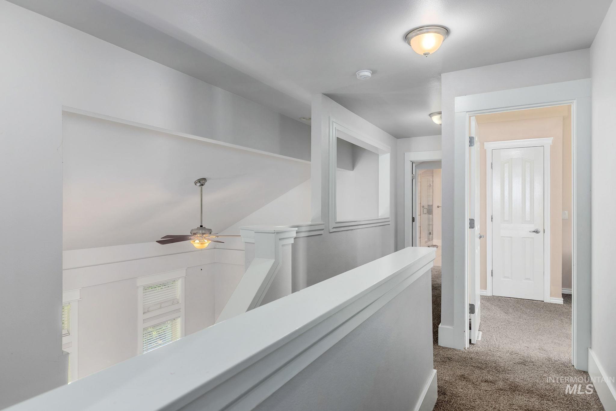 Hallway featuring dark colored carpet and an upstairs landing