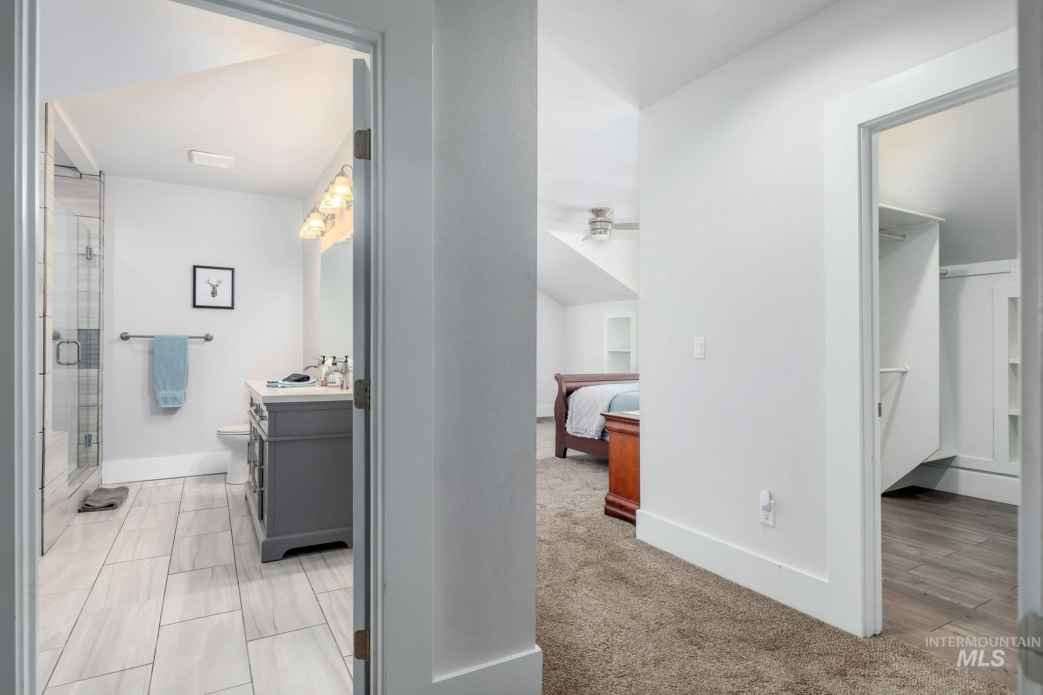 Ensuite bathroom featuring vanity, a shower stall, and ceiling fan