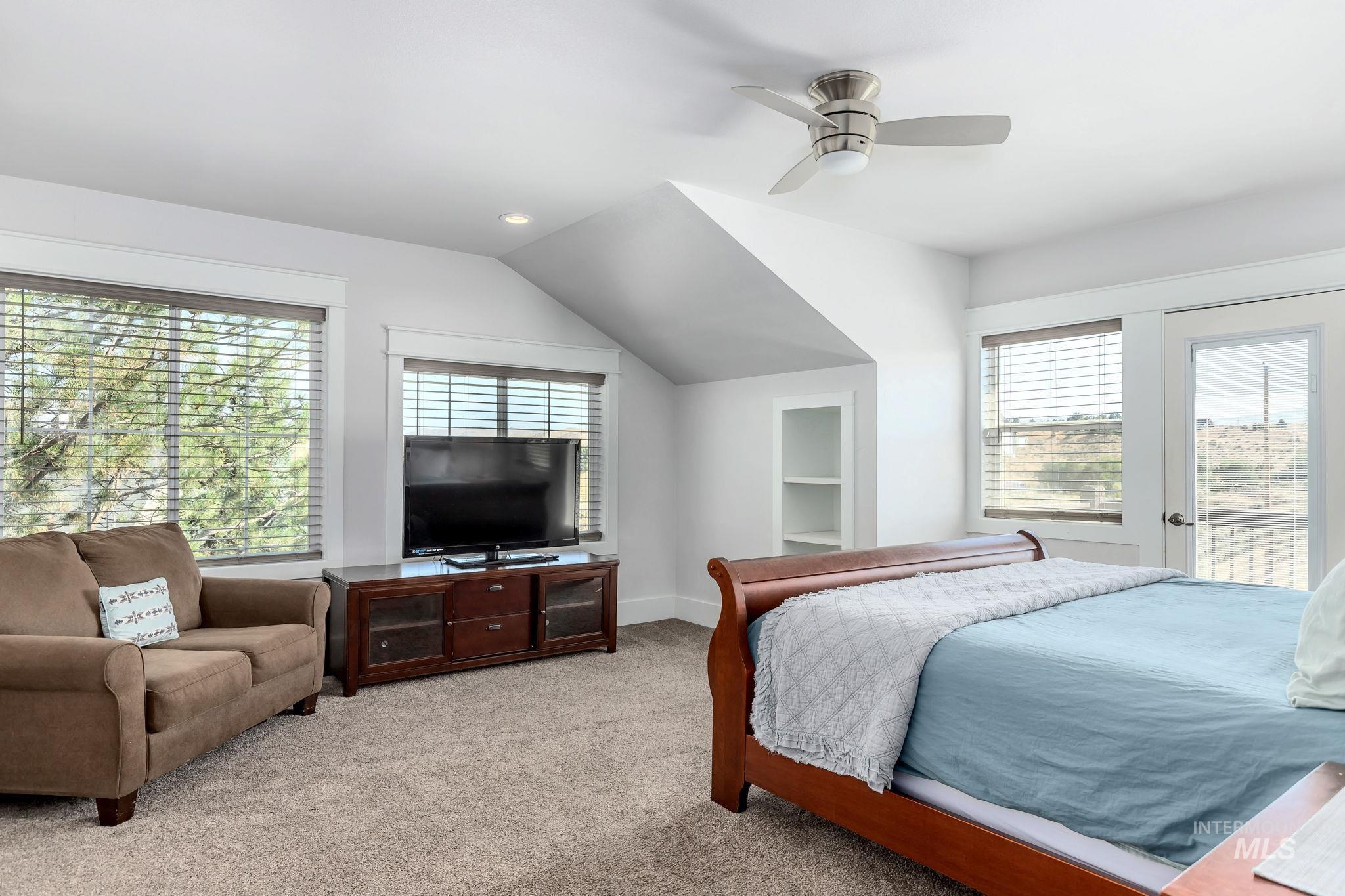 Bedroom featuring multiple windows, access to outside, light carpet, vaulted ceiling, and recessed lighting