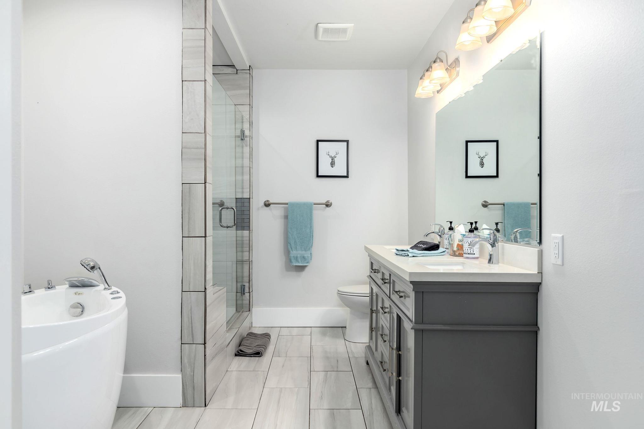 Bathroom with vanity, a bathtub, and a stall shower