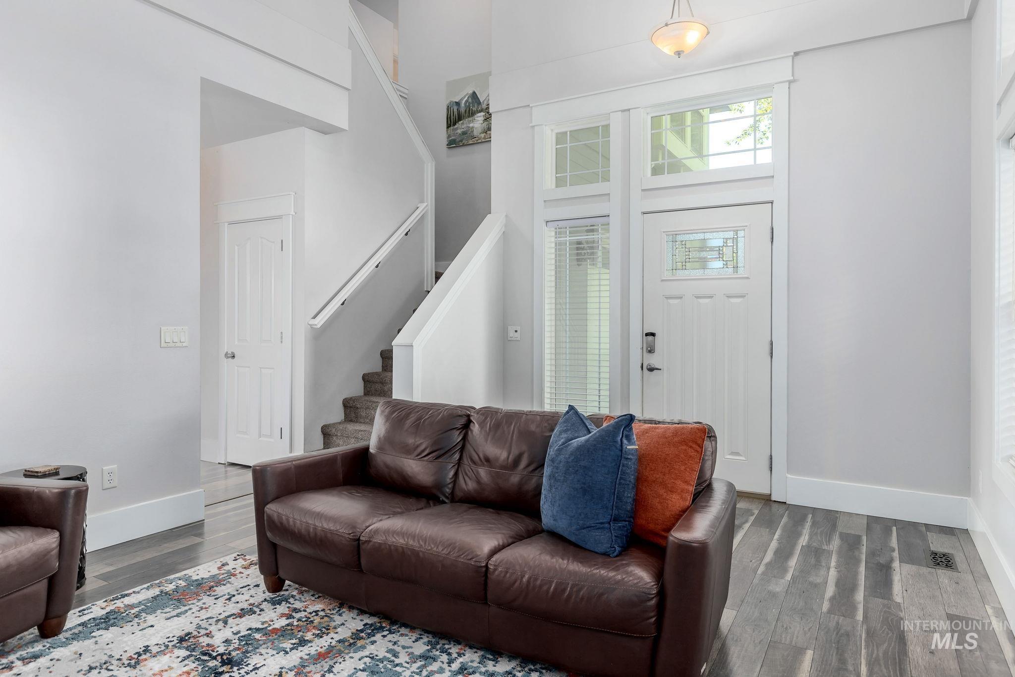 Living room with stairs, wood finished floors, and a high ceiling