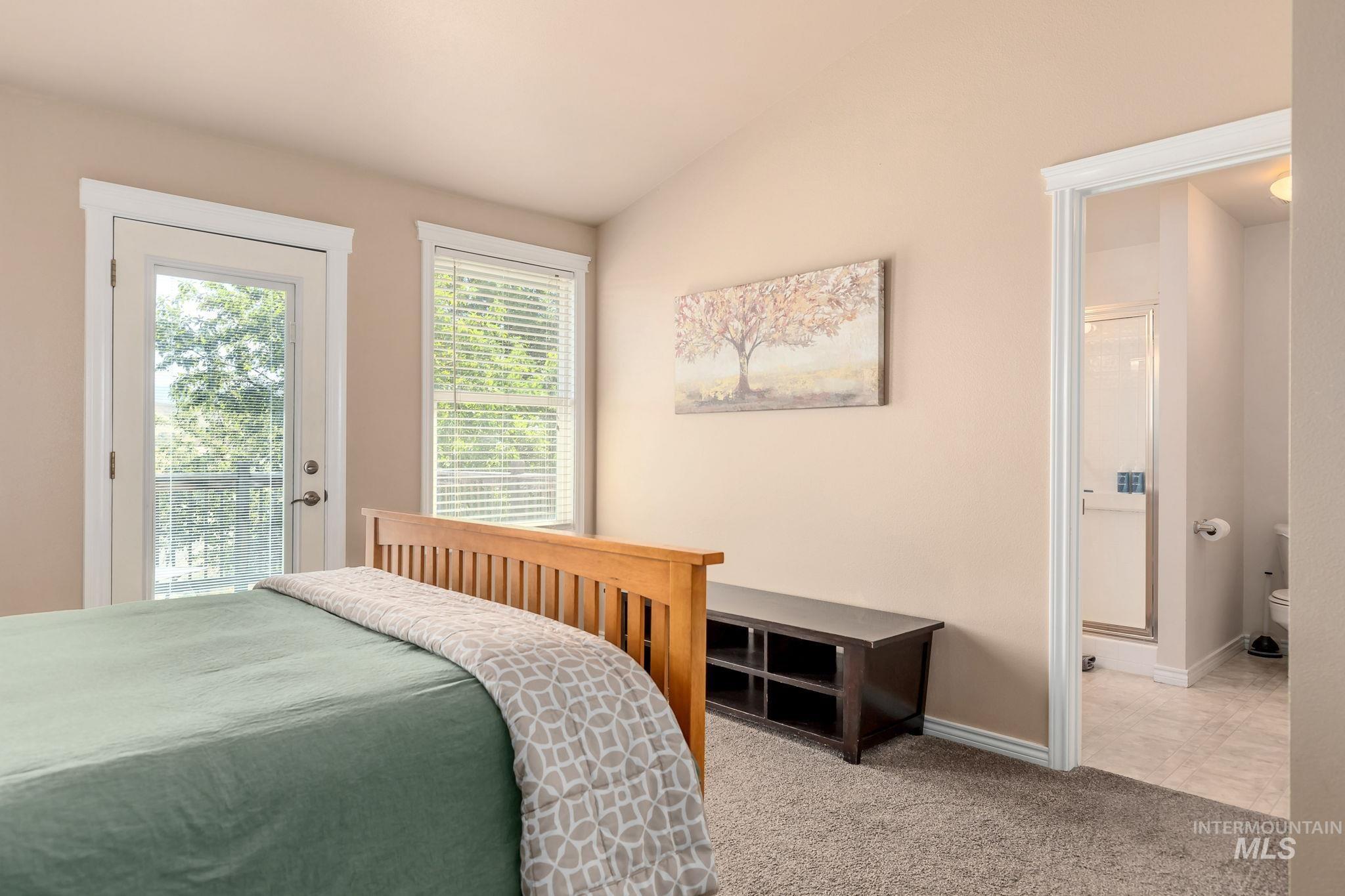 Bedroom featuring carpet, vaulted ceiling, access to exterior, and connected bathroom