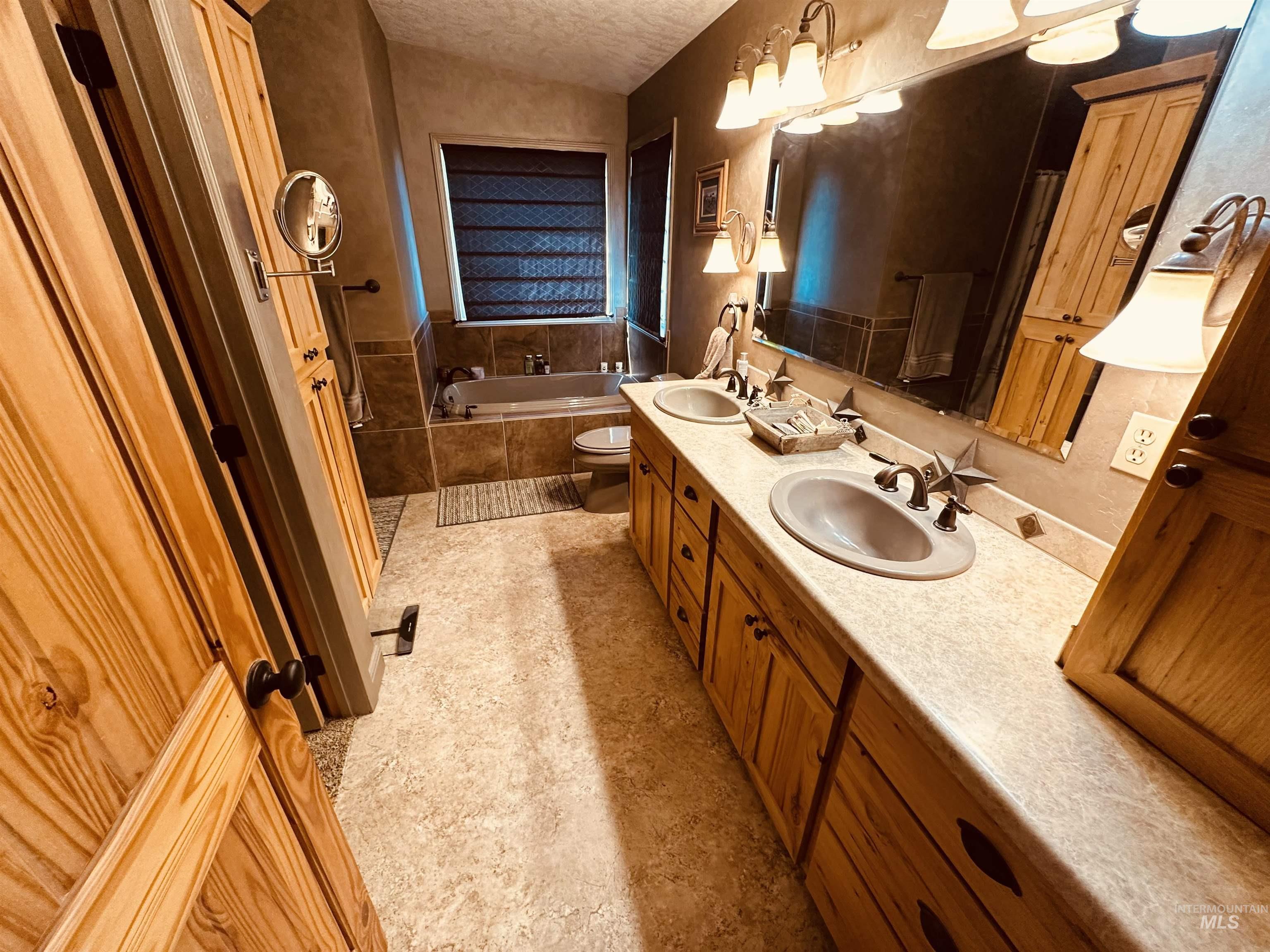 Bathroom featuring a bath, double vanity, and a textured ceiling