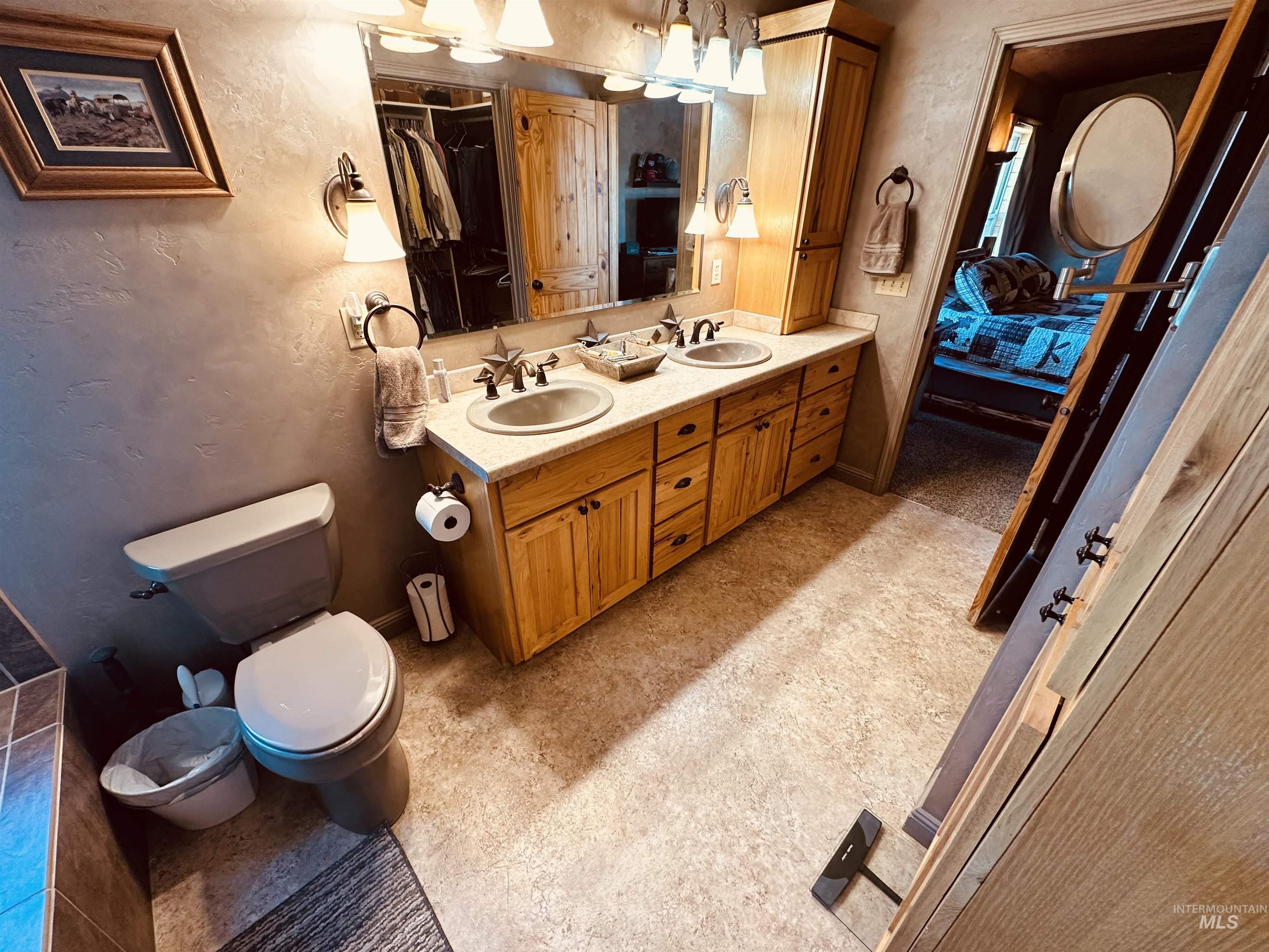 Bathroom with a textured wall, ensuite bathroom, and double vanity