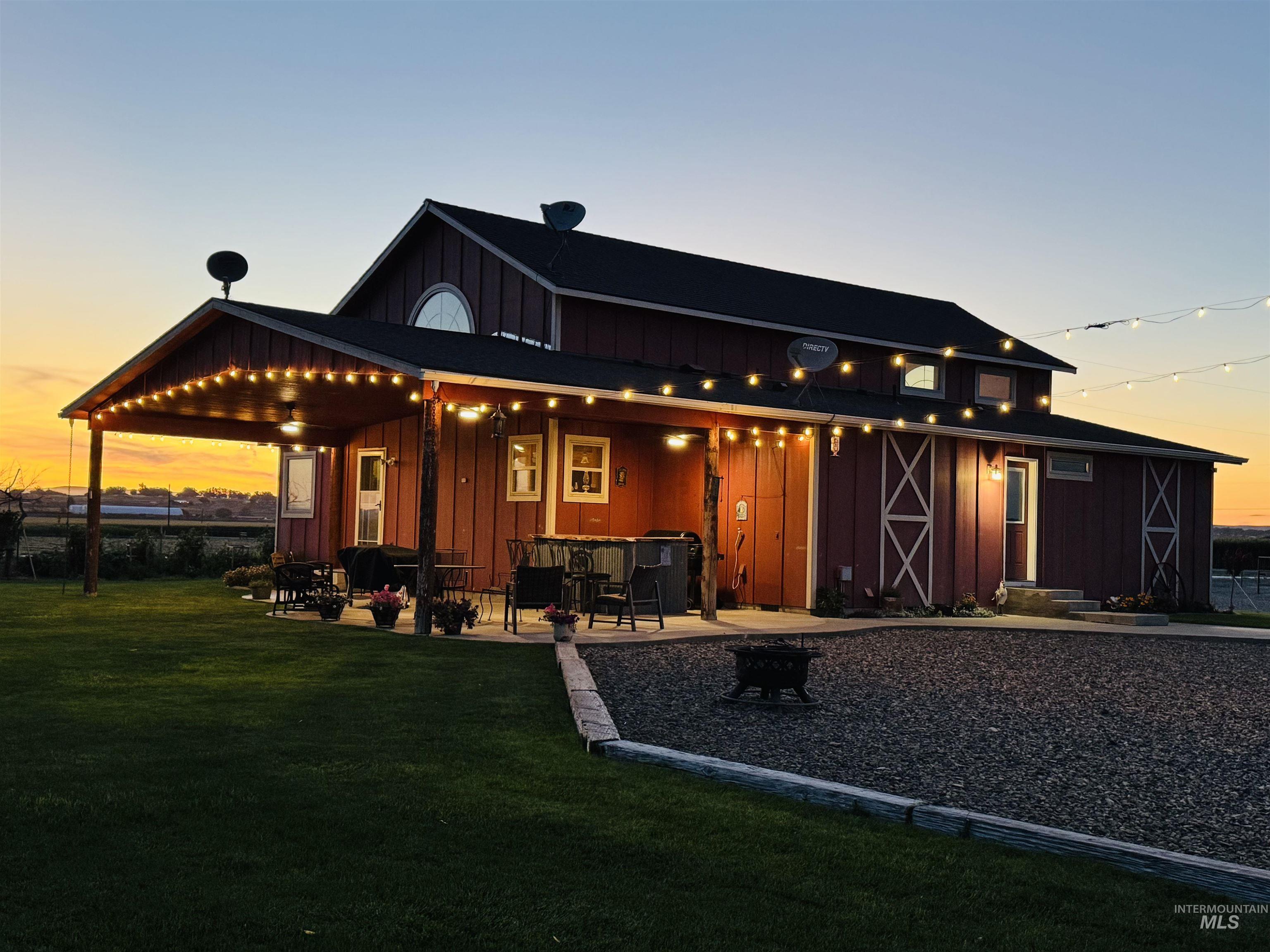 Back of house at dusk with board and batten siding, a lawn, a patio area, and an outdoor fire pit