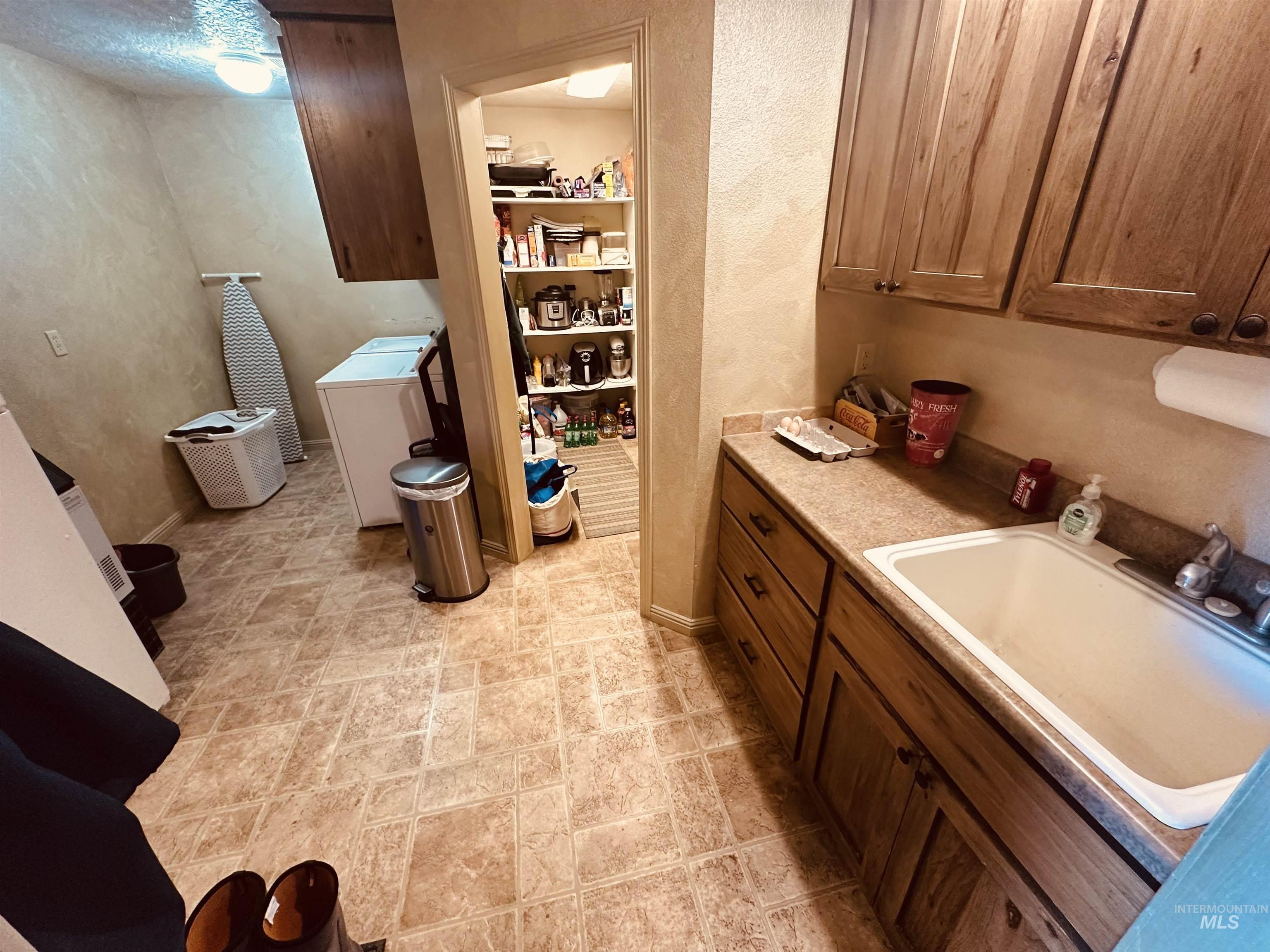 Laundry area featuring a textured wall, washer / dryer, and stone finish flooring