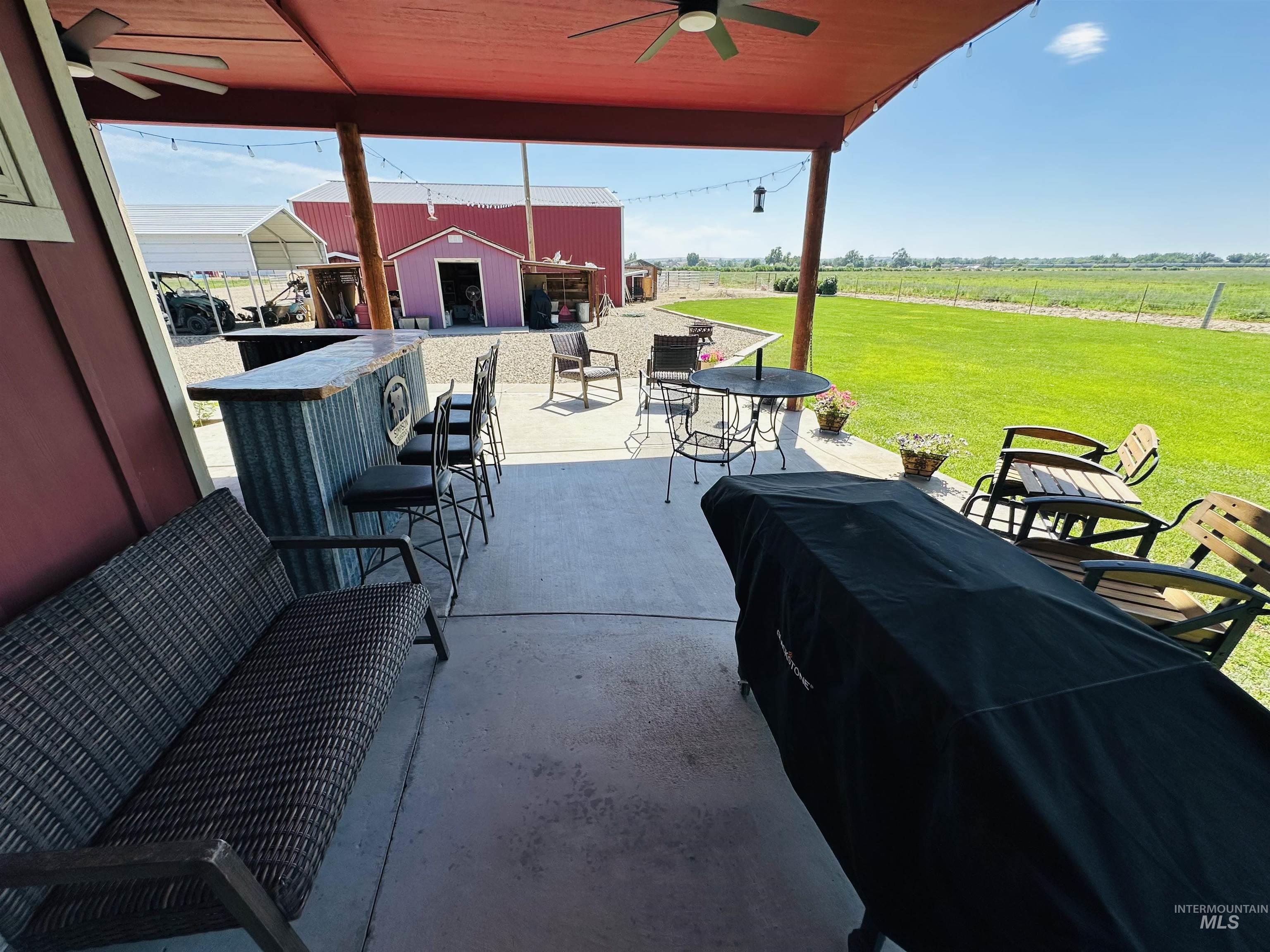 View of patio with ceiling fan, a view of rural / pastoral area, and an outdoor structure