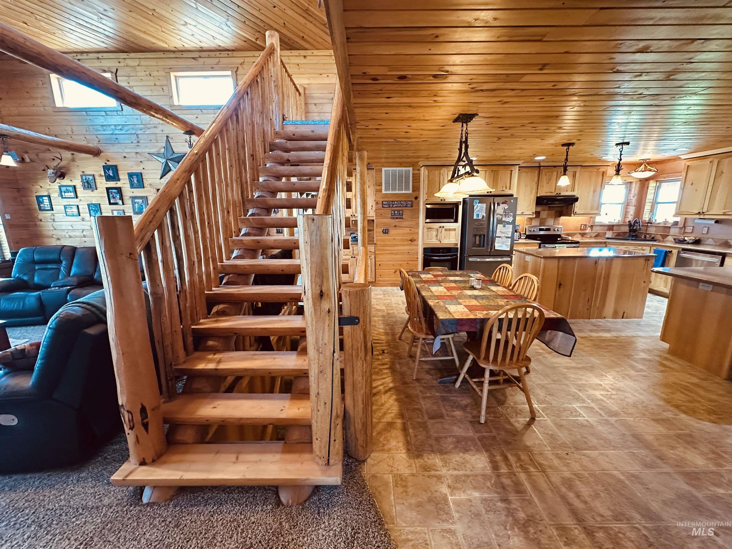 featuring wooden ceiling, stairs, light stone finish floors, and wooden walls