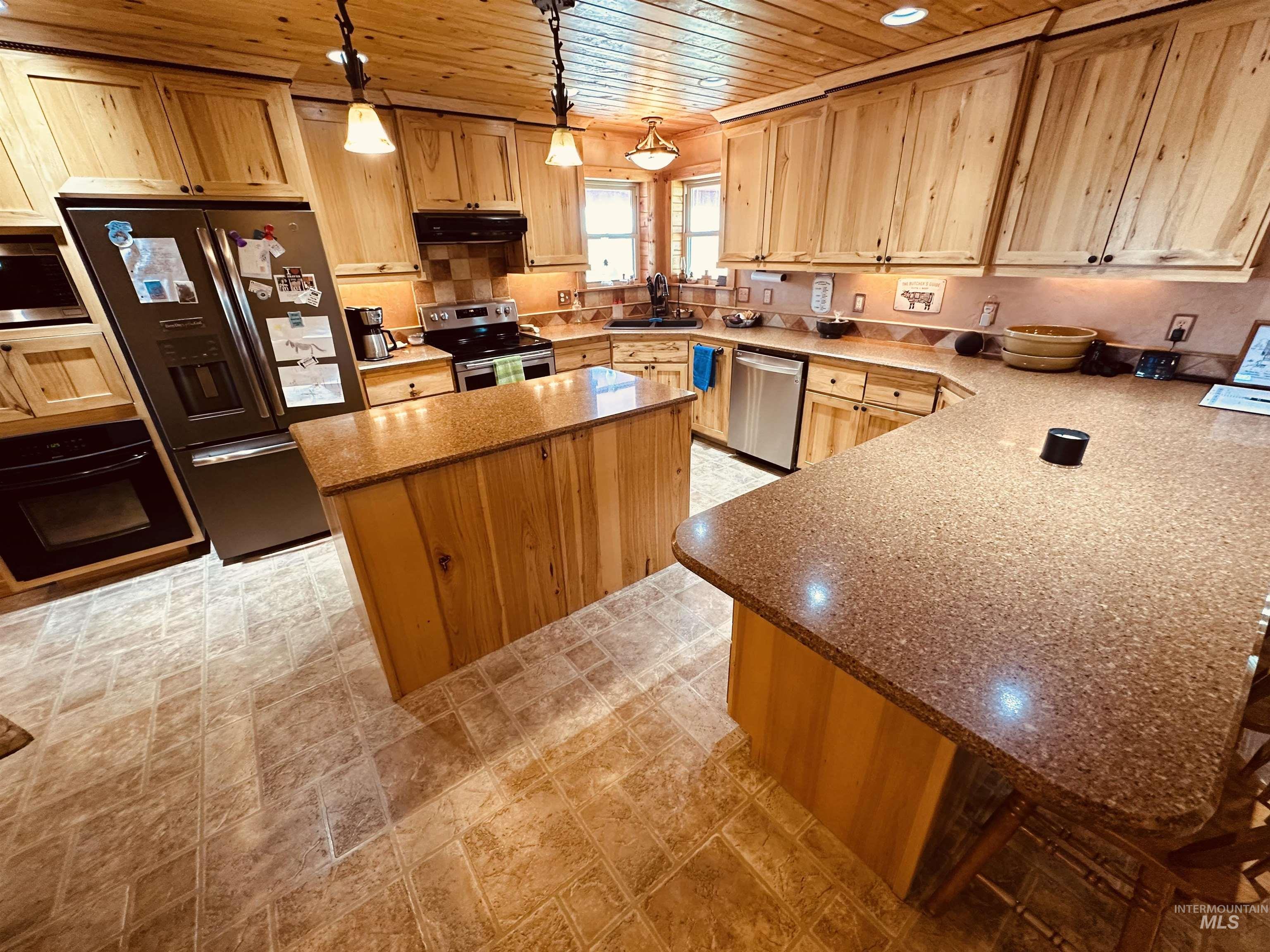Kitchen with wood ceiling, stainless steel appliances, stone countertops, a kitchen island, and light brown cabinets