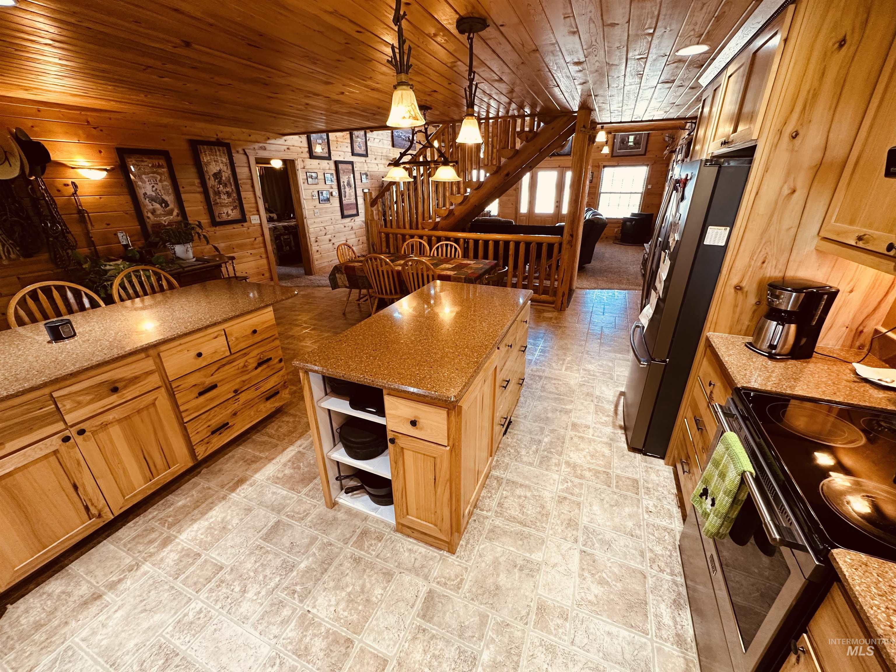 Kitchen featuring wooden walls, electric range, wooden ceiling, light stone counters, and freestanding refrigerator