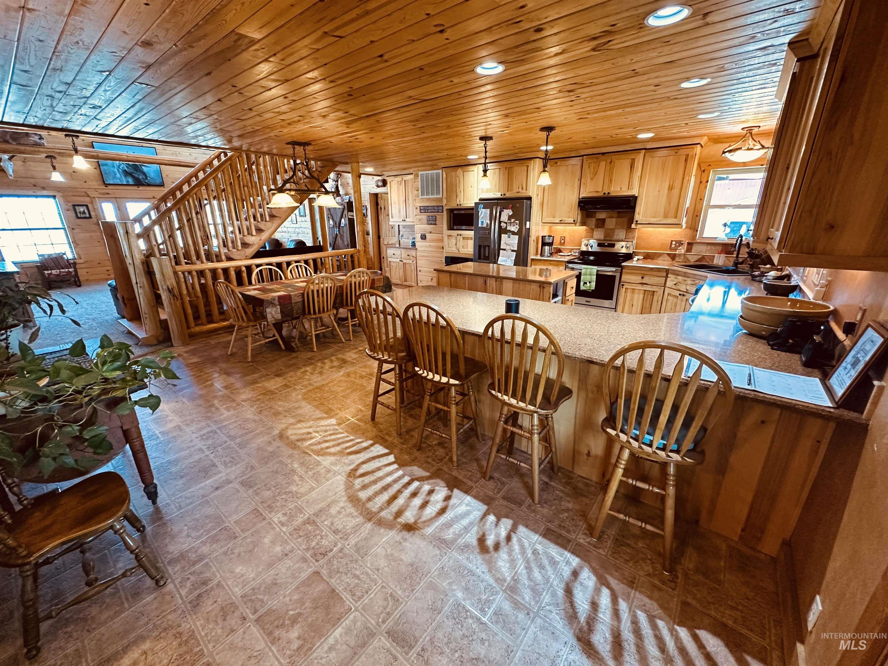 Kitchen featuring wood ceiling, stainless steel appliances, a peninsula, wood walls, and recessed lighting