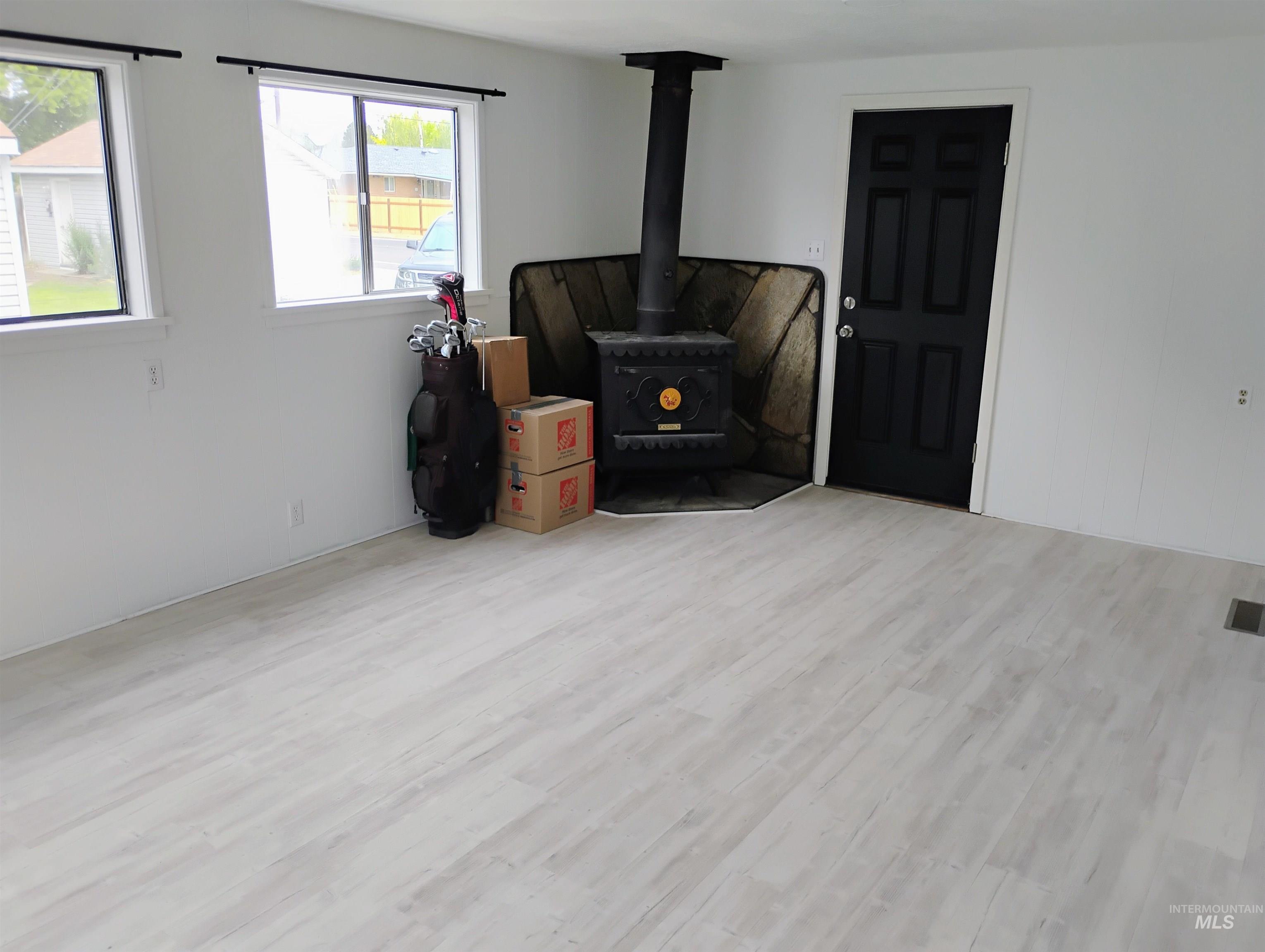 Living room with a wood stove and wood finished floors
