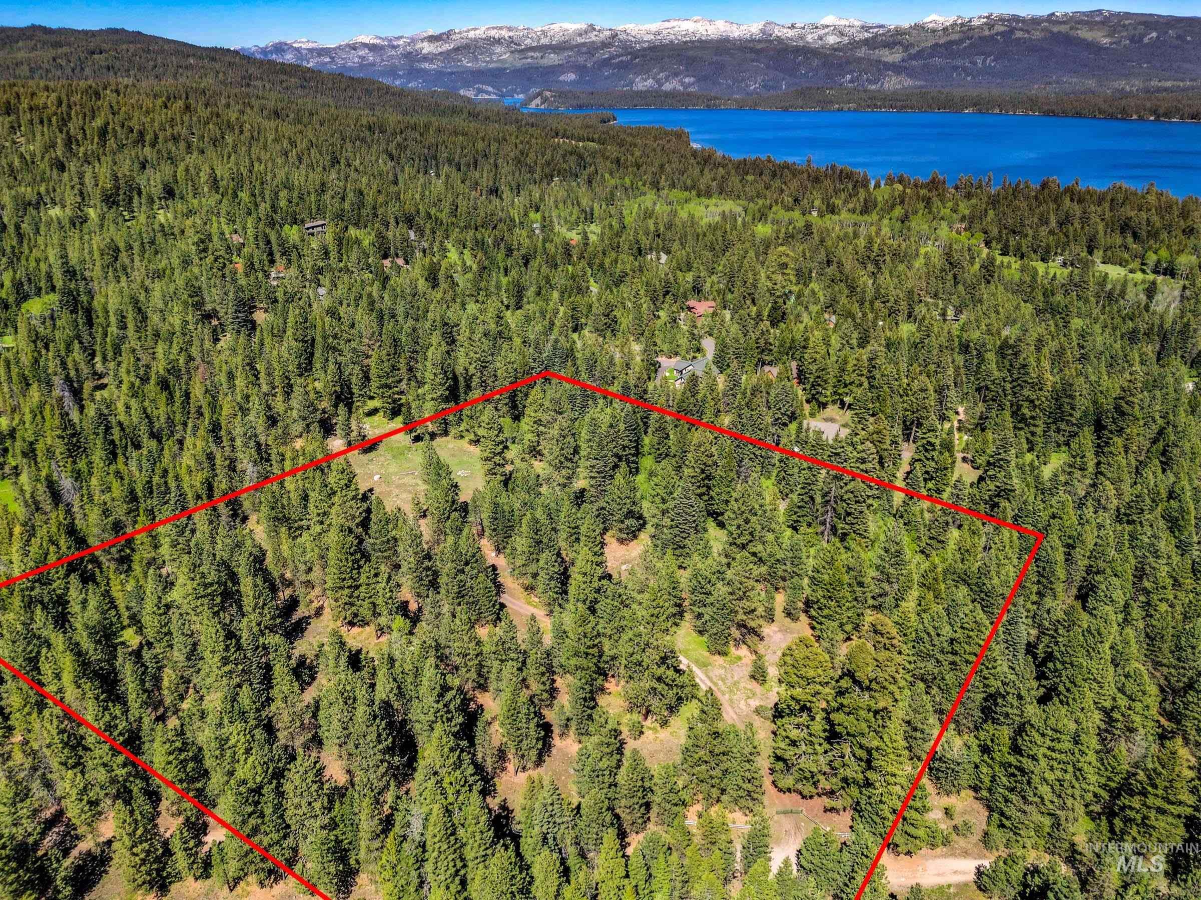 Aerial view of property and surrounding area featuring a mountain backdrop and property parcel outlined