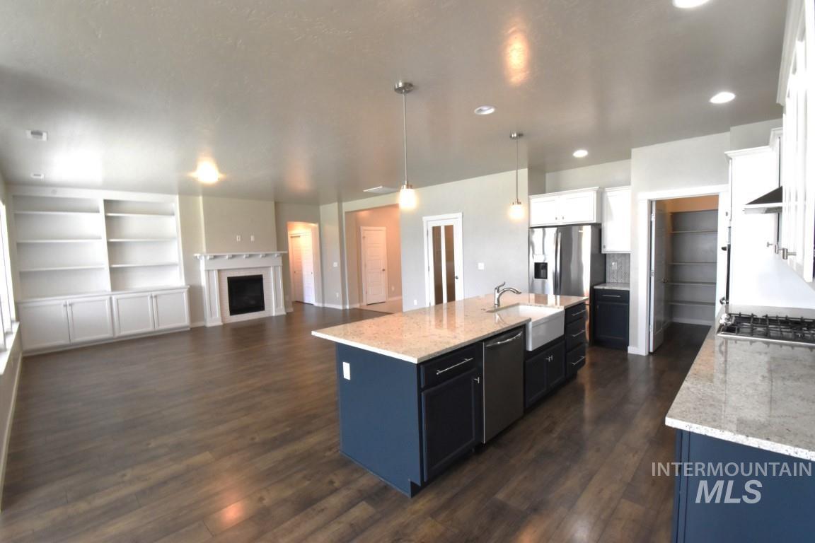 Kitchen with dark wood-type flooring, stainless steel appliances, an island with sink, white cabinets, and recessed lighting