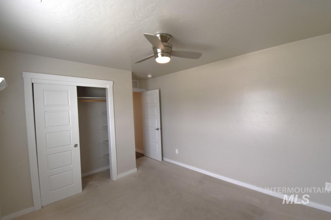 Unfurnished bedroom featuring a closet, ceiling fan, and light colored carpet