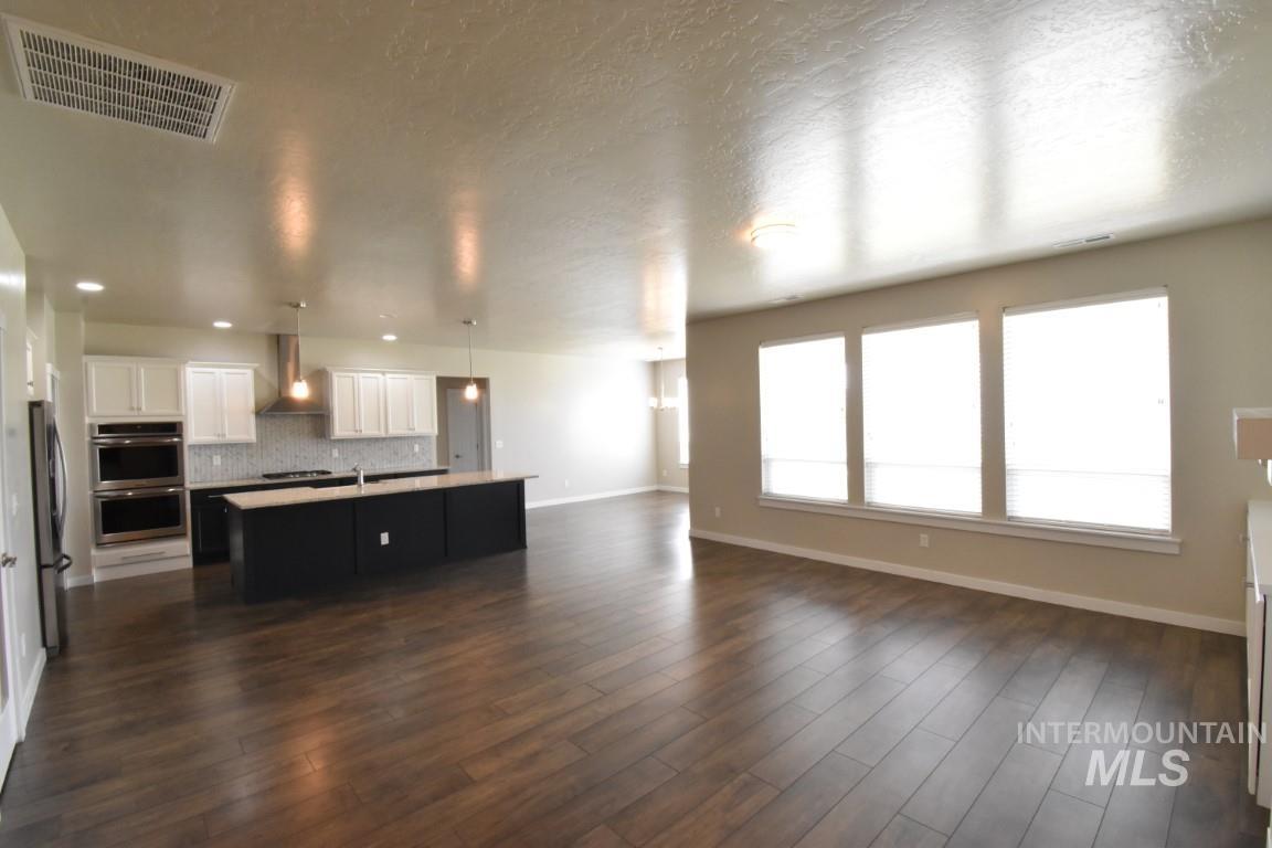 Unfurnished living room featuring dark wood-style flooring and a textured ceiling
