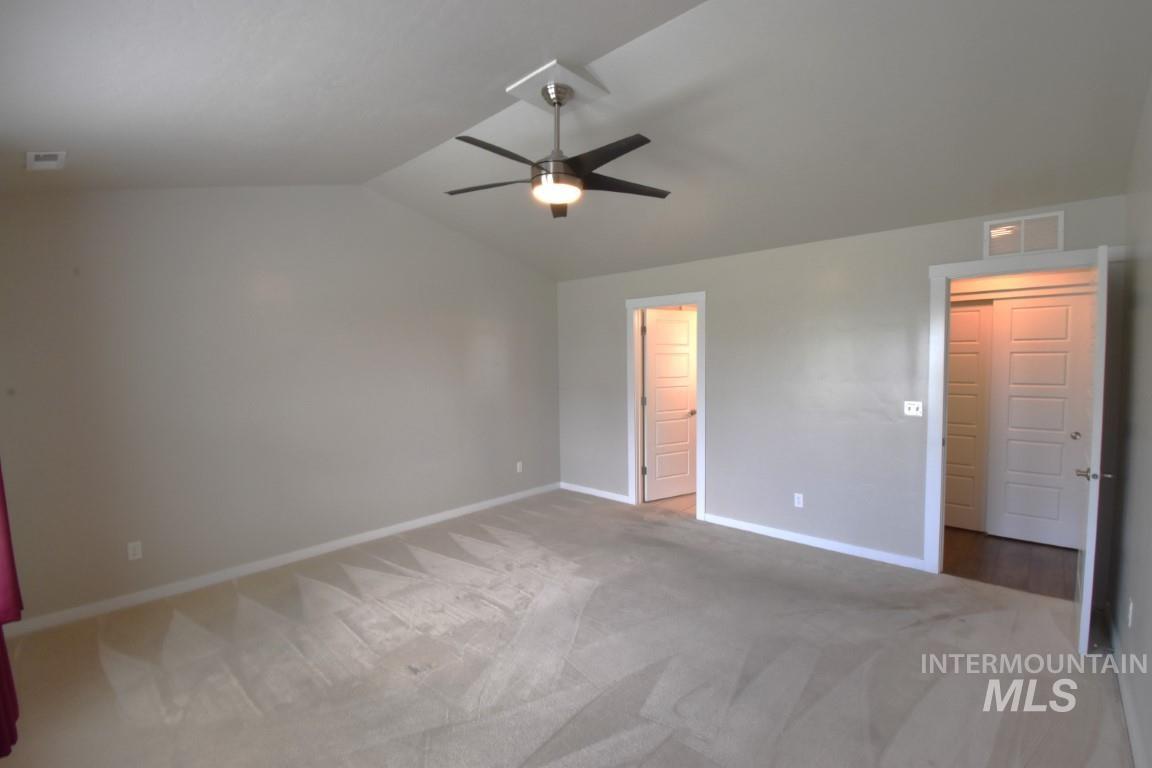 Unfurnished bedroom with vaulted ceiling, carpet floors, and ceiling fan
