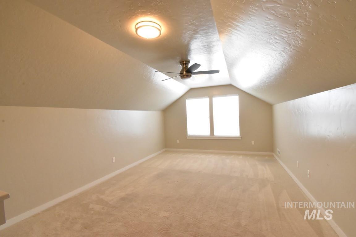 Bonus room with light carpet, vaulted ceiling, a textured ceiling, and a ceiling fan