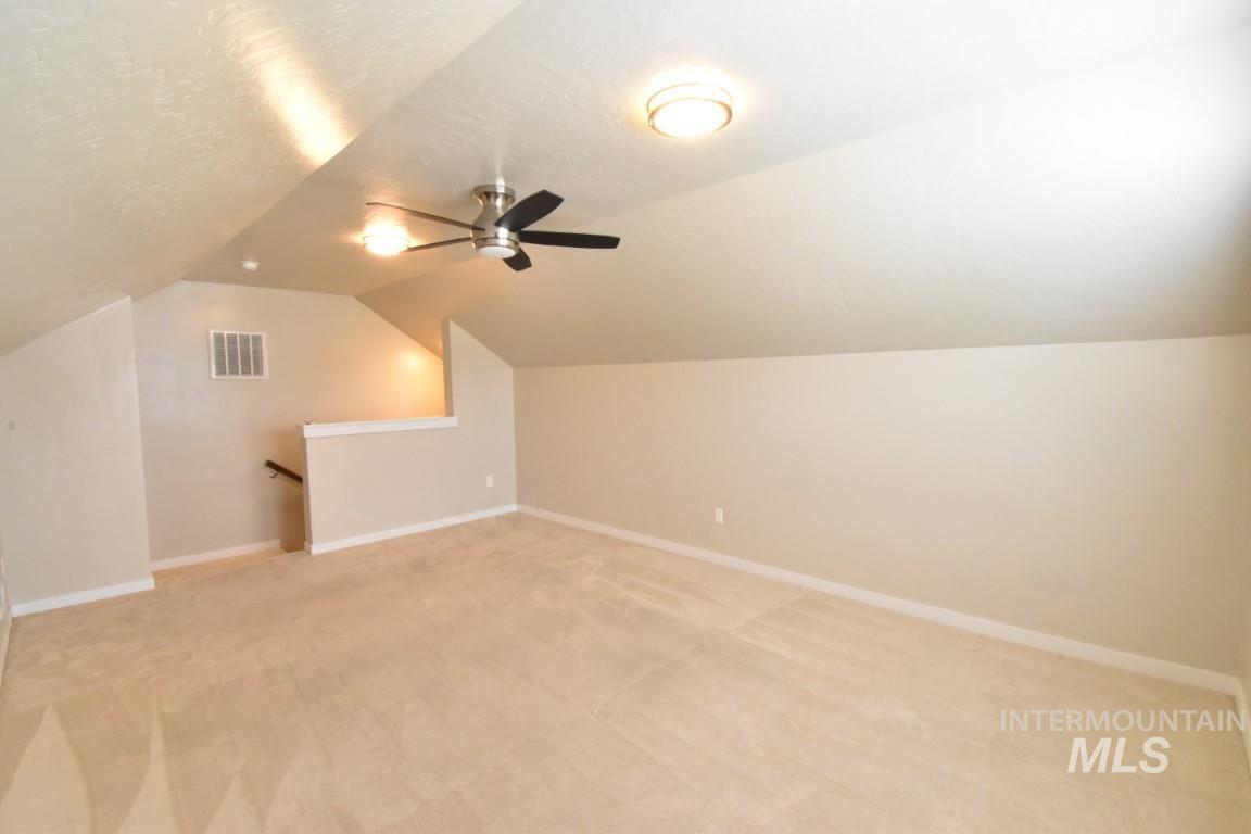 Bonus room featuring light carpet, lofted ceiling, and ceiling fan