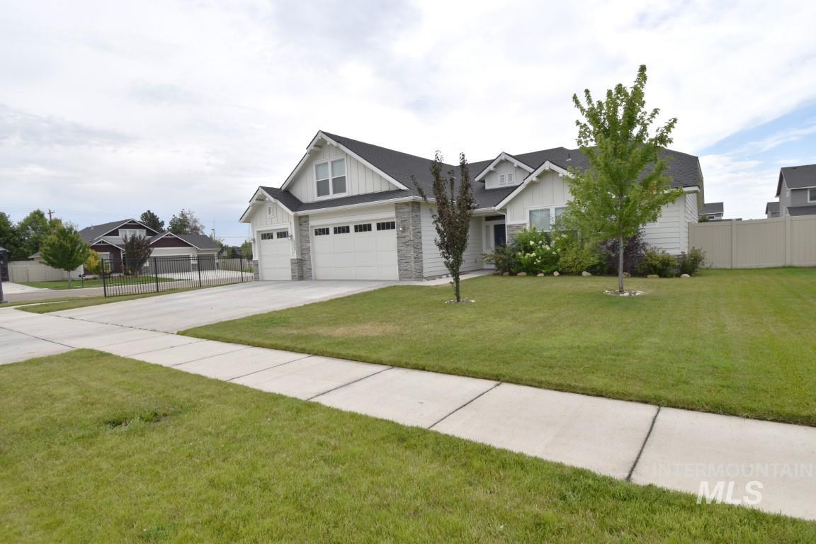 Craftsman-style home featuring board and batten siding, driveway, stone siding, and an attached garage
