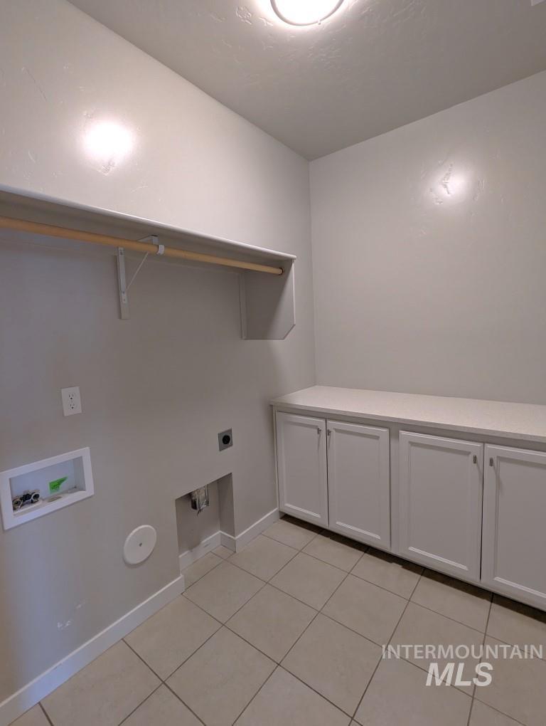 Washroom with hookup for an electric dryer, hookup for a washing machine, light tile patterned floors, and hookup for a gas dryer