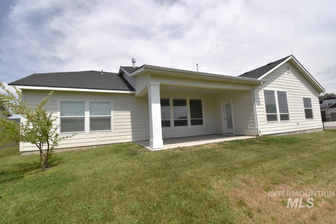 Back of property with a patio area, a lawn, and roof with shingles