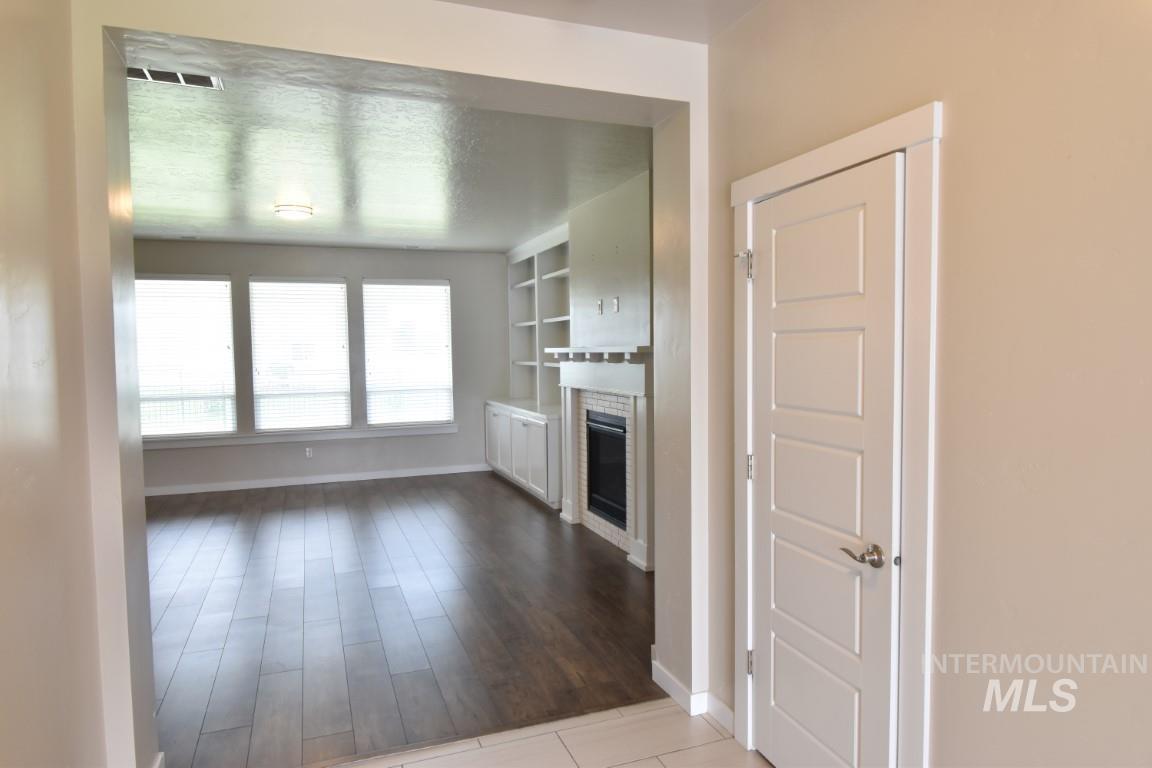Unfurnished living room featuring a glass covered fireplace and wood finished floors