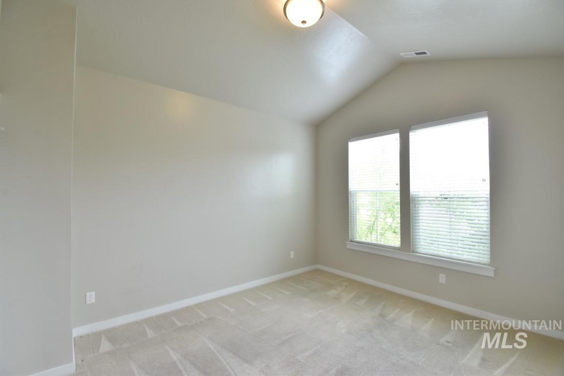 Spare room featuring lofted ceiling and light colored carpet